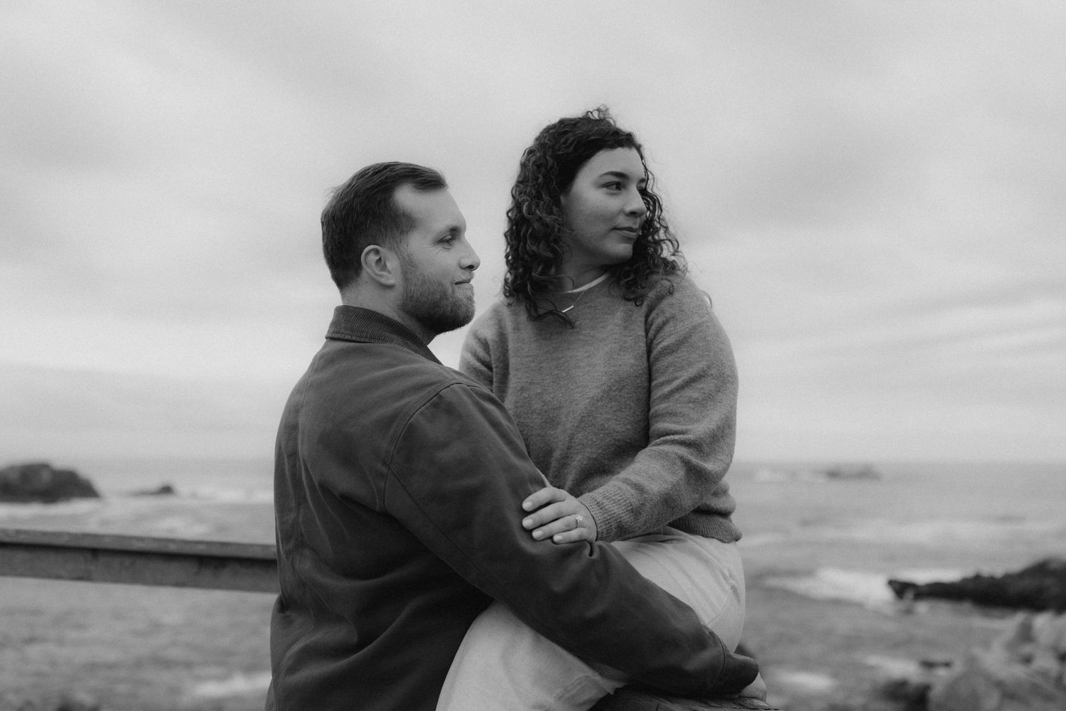 A couple embraces on a cloudy day against a dramatic overcast sky.