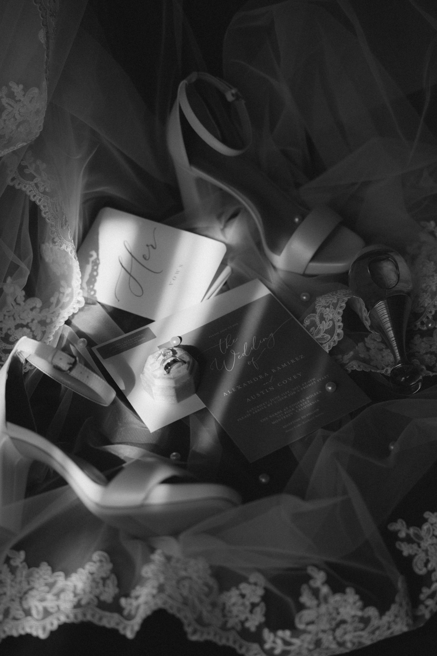 Black and white artistic photo of wedding rings and delicate lace details.