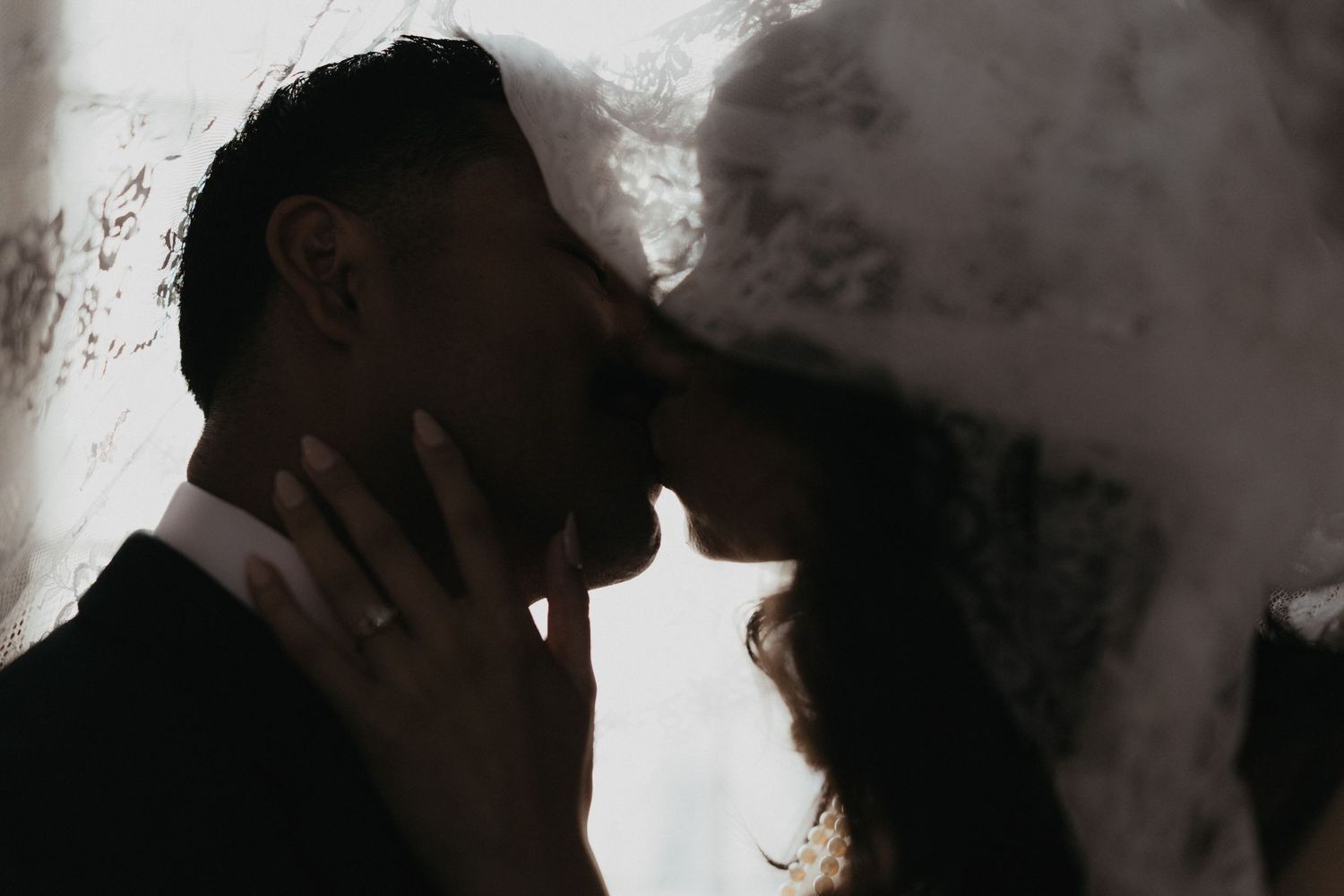 A shadowy intimate portrait of newlyweds sharing a tender moment.