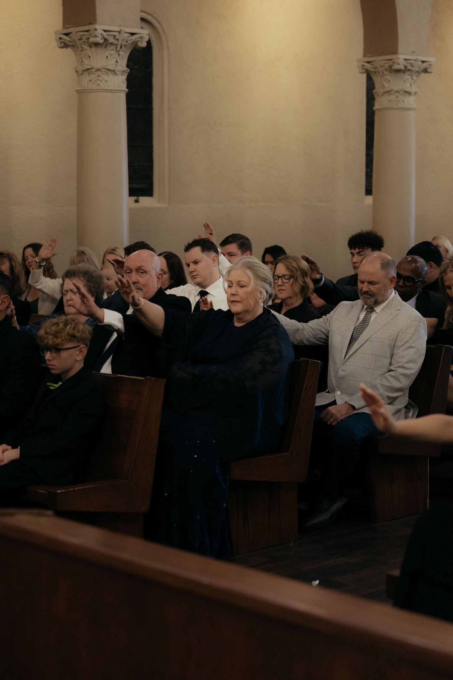 A congregation of people sitting in wooden pews inside a church during a service.