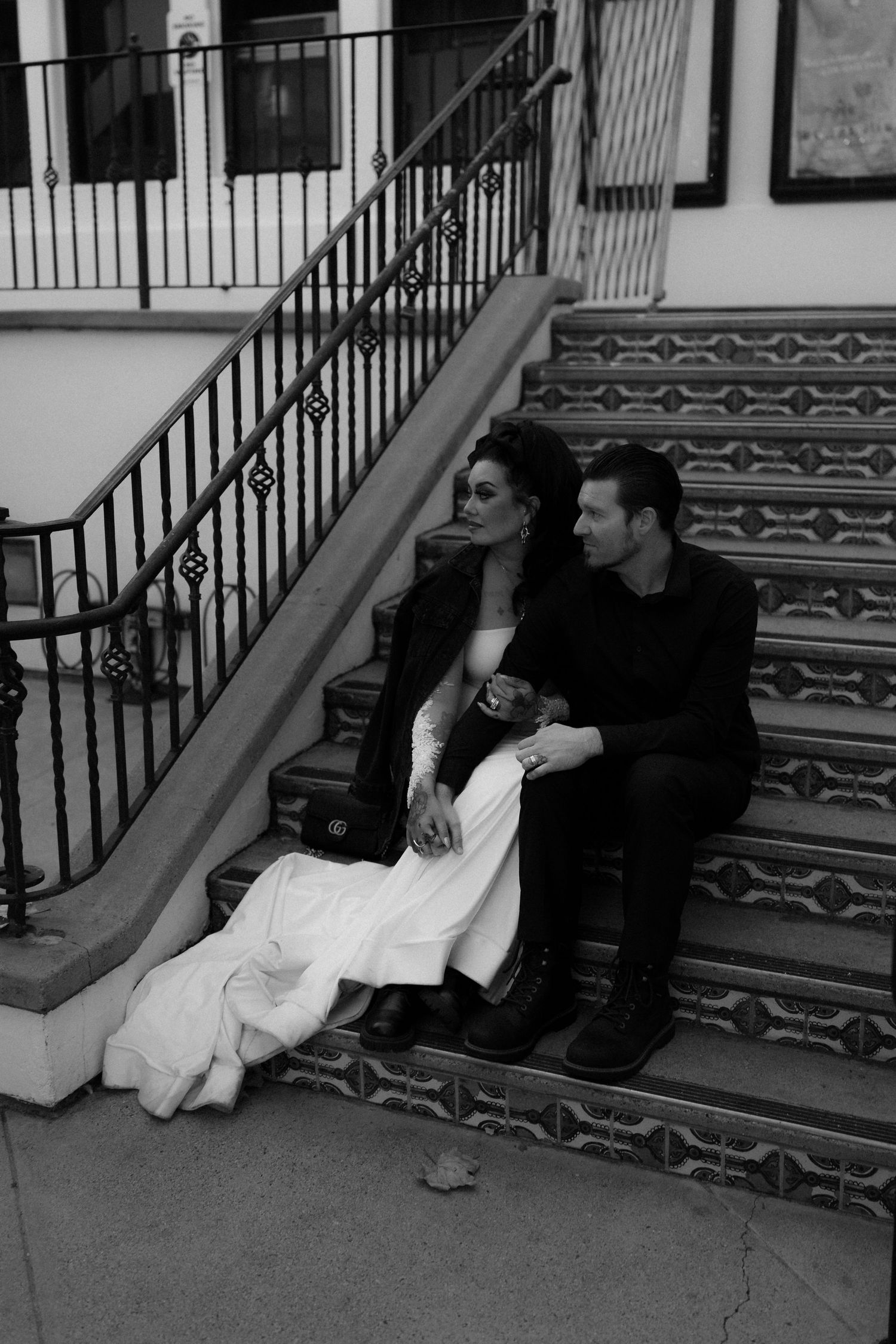 A couple sits together on decorative tiled steps in black and white photography.