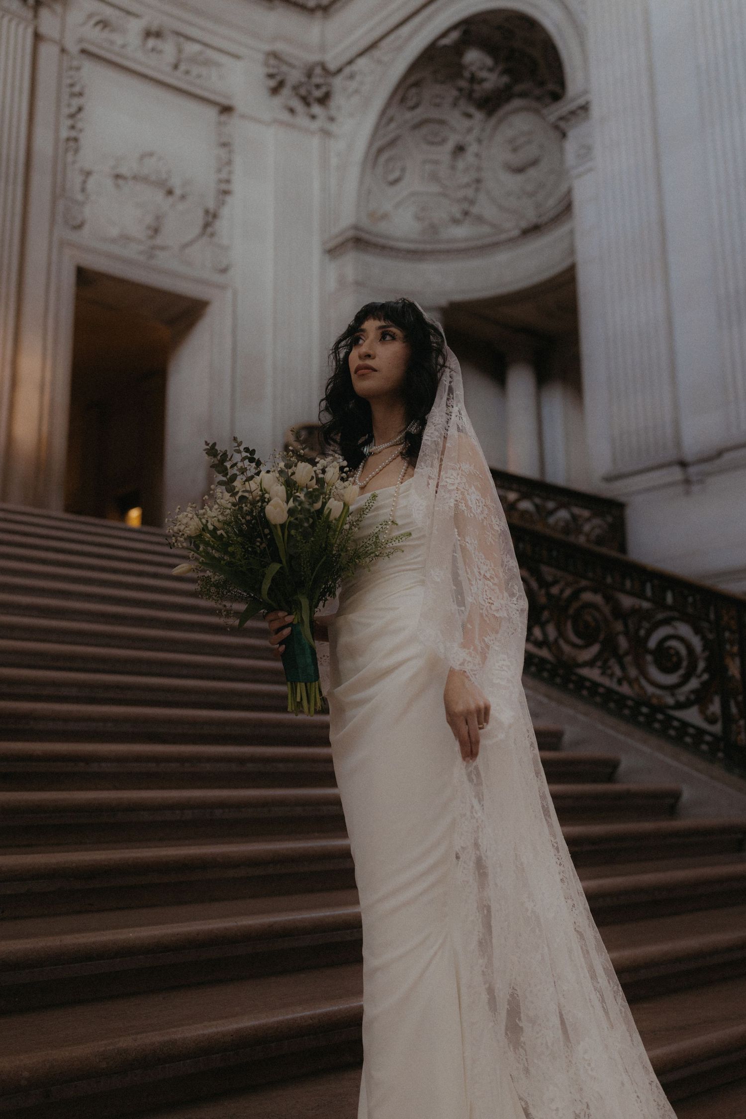 Elegant bridal portraits on historic stone steps with ornate architectural details.