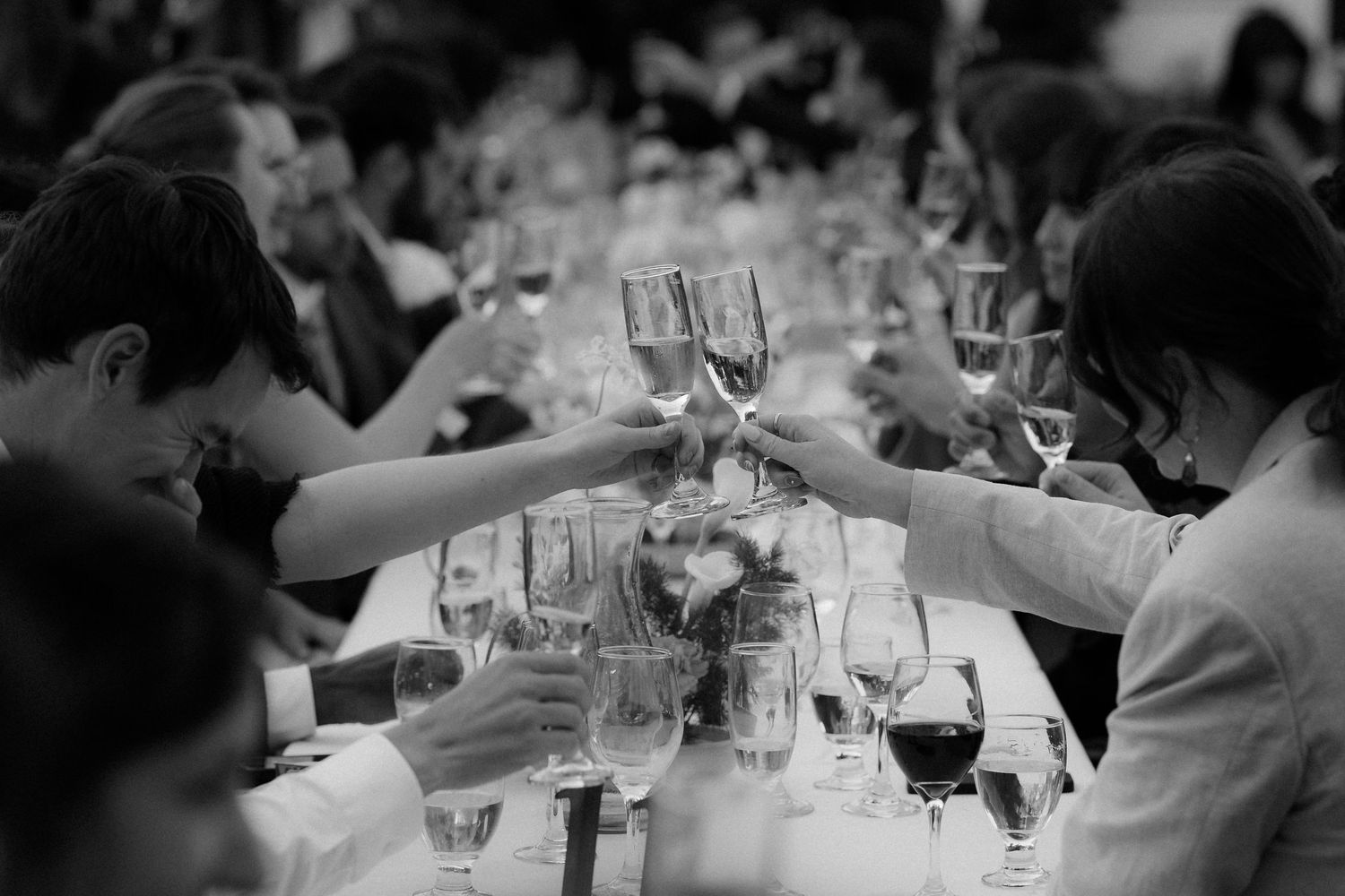 Black and white photo showing wine glasses and table settings at an elegant dinner party or reception.