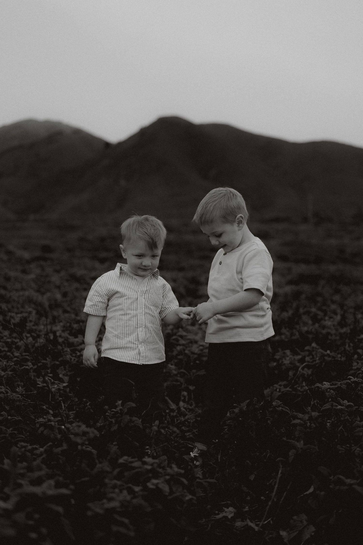 Two young children in white shirts explore a dark field together in this vintage black and white photograph.