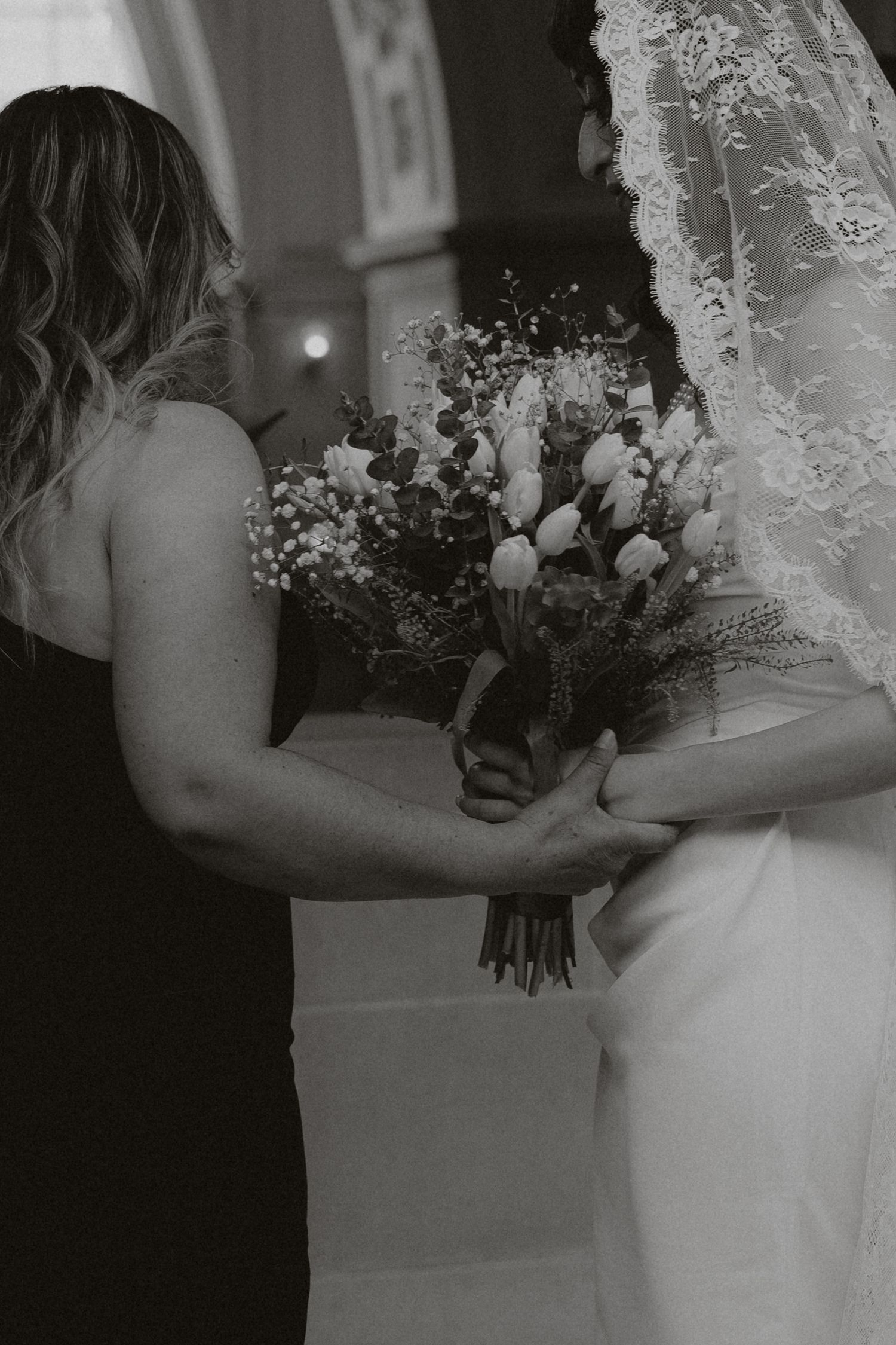 Wedding party members holding floral bouquets in an elegant hallway setting.