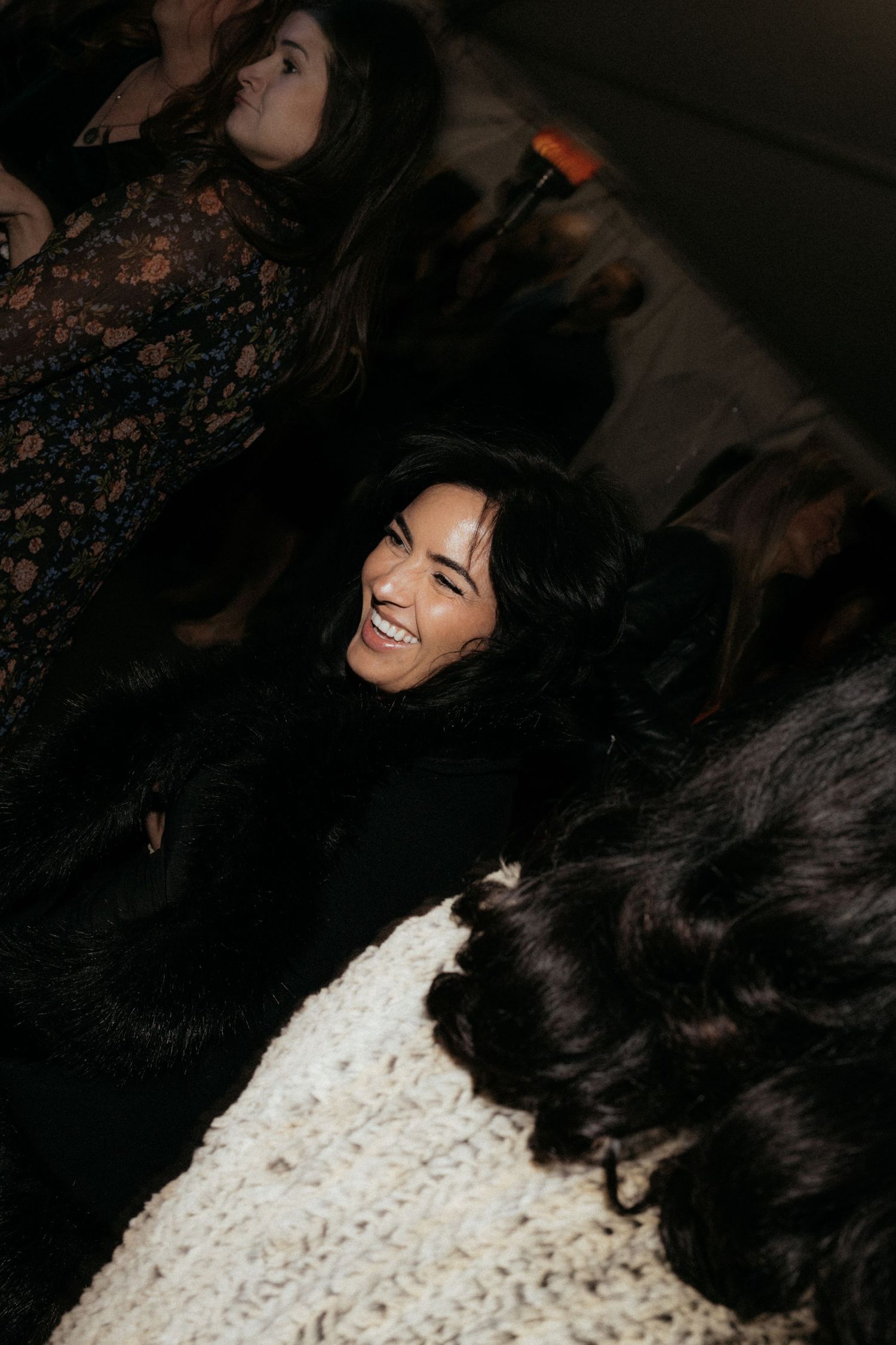 Partygoers laughing and having fun in dark formal attire at a nighttime event.
