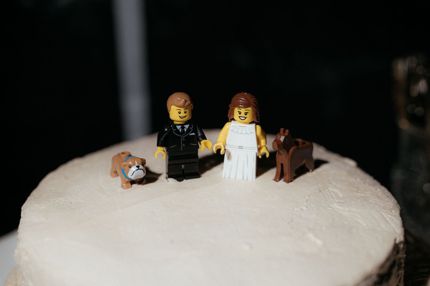 Small toy figurines stand atop a snowy white surface with dark bottles in the background.
