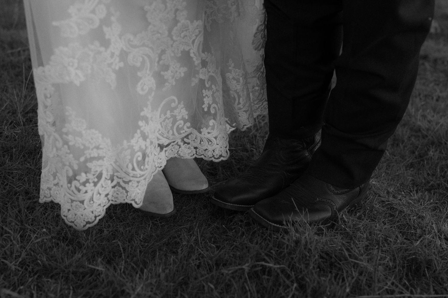 Black and white detail shot of bride and groom's feet on grass.