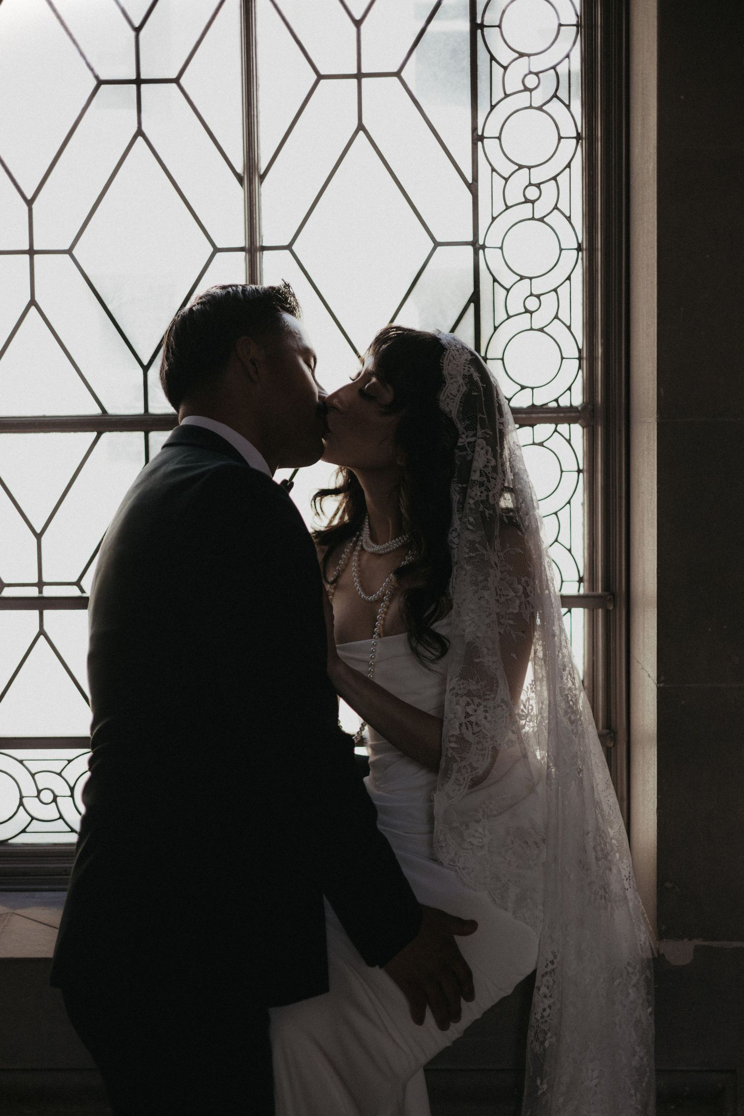 A romantic wedding couple stands in silhouette against ornate windows in a sequence of four similar photos.