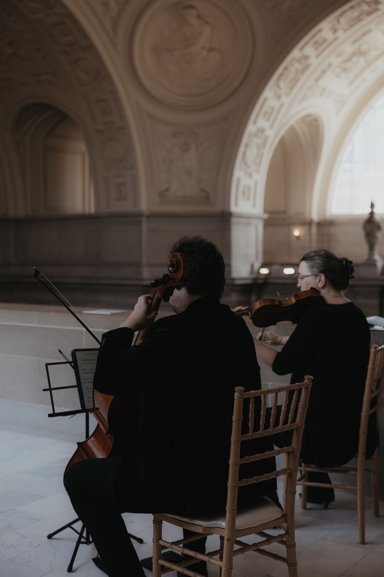 Musicians perform in an elegant hall with arched ceilings and classical architecture.