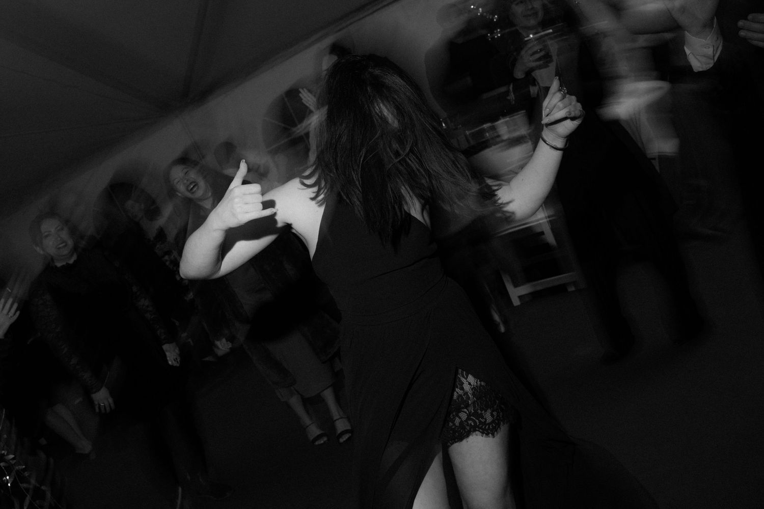 A dark silhouette dances energetically against a blurred party background.