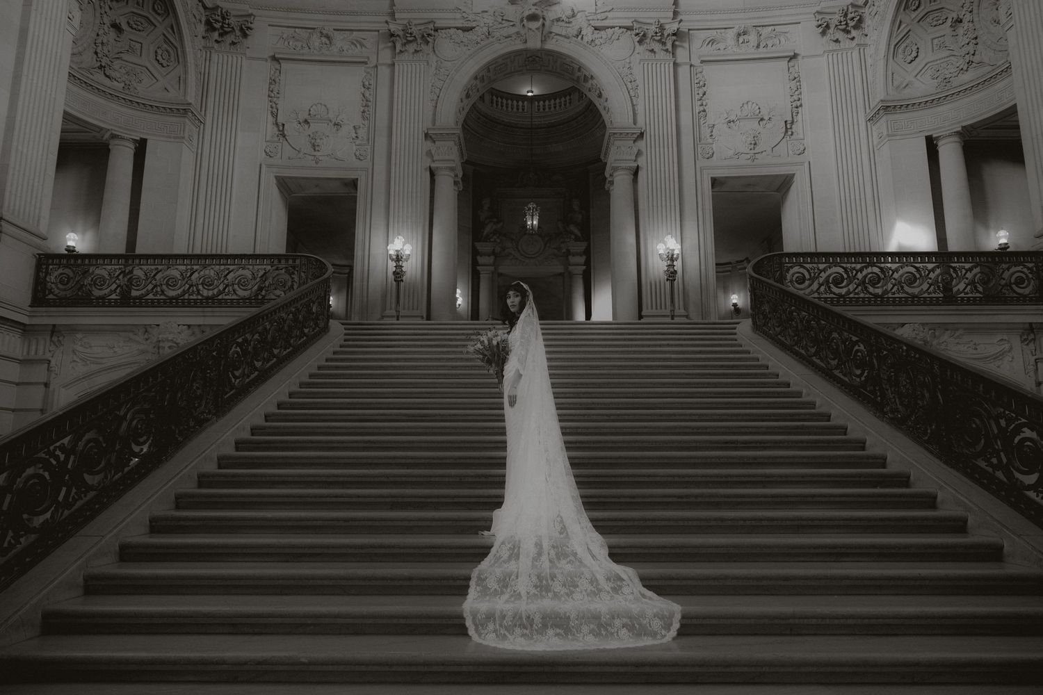 Grand marble staircase in an ornate historic building with decorative railings and architectural details.