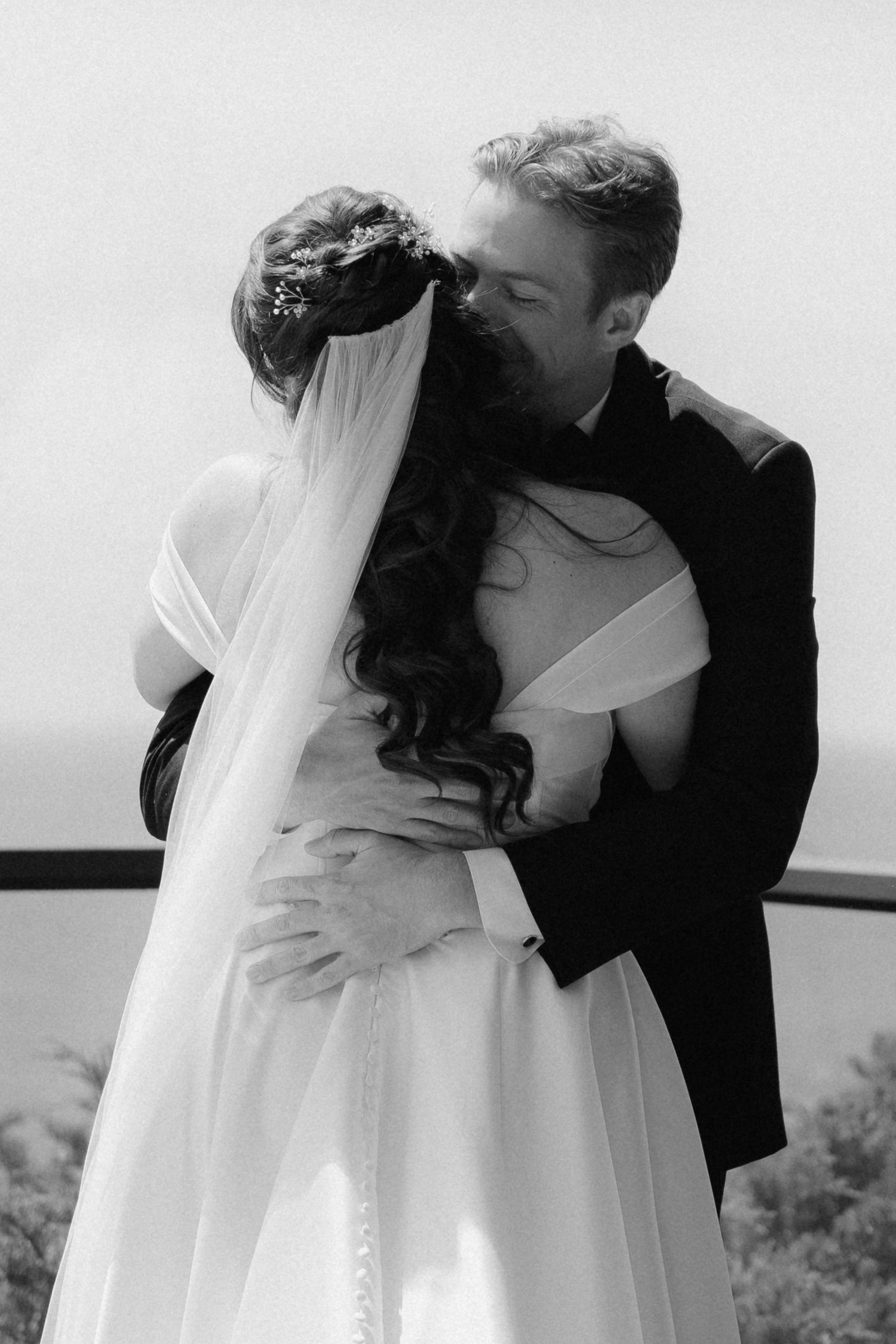 Black and white photo of a bride and groom sharing a romantic embrace on their wedding day.