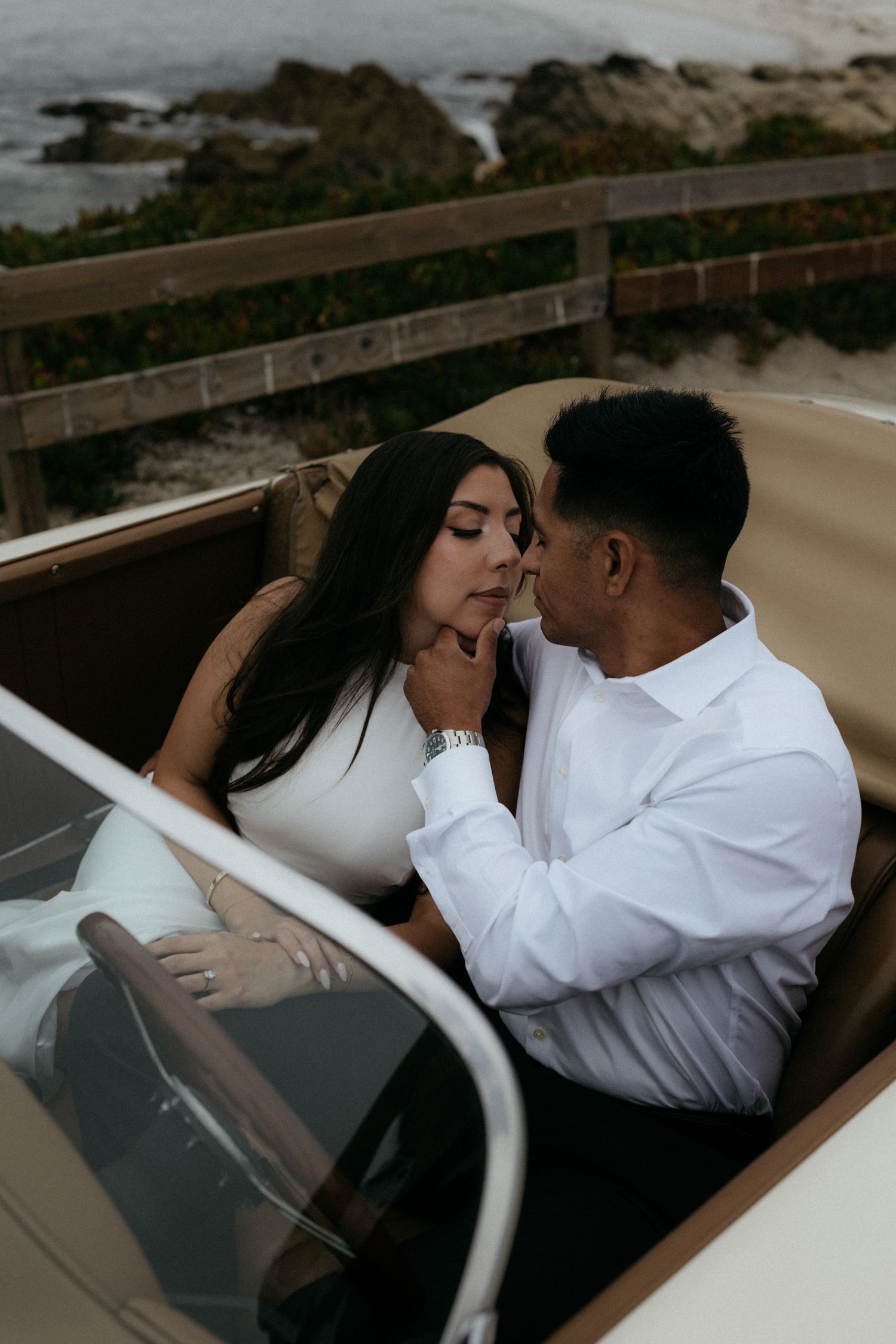 Couple sharing a romantic moment in a vintage convertible car by the ocean.