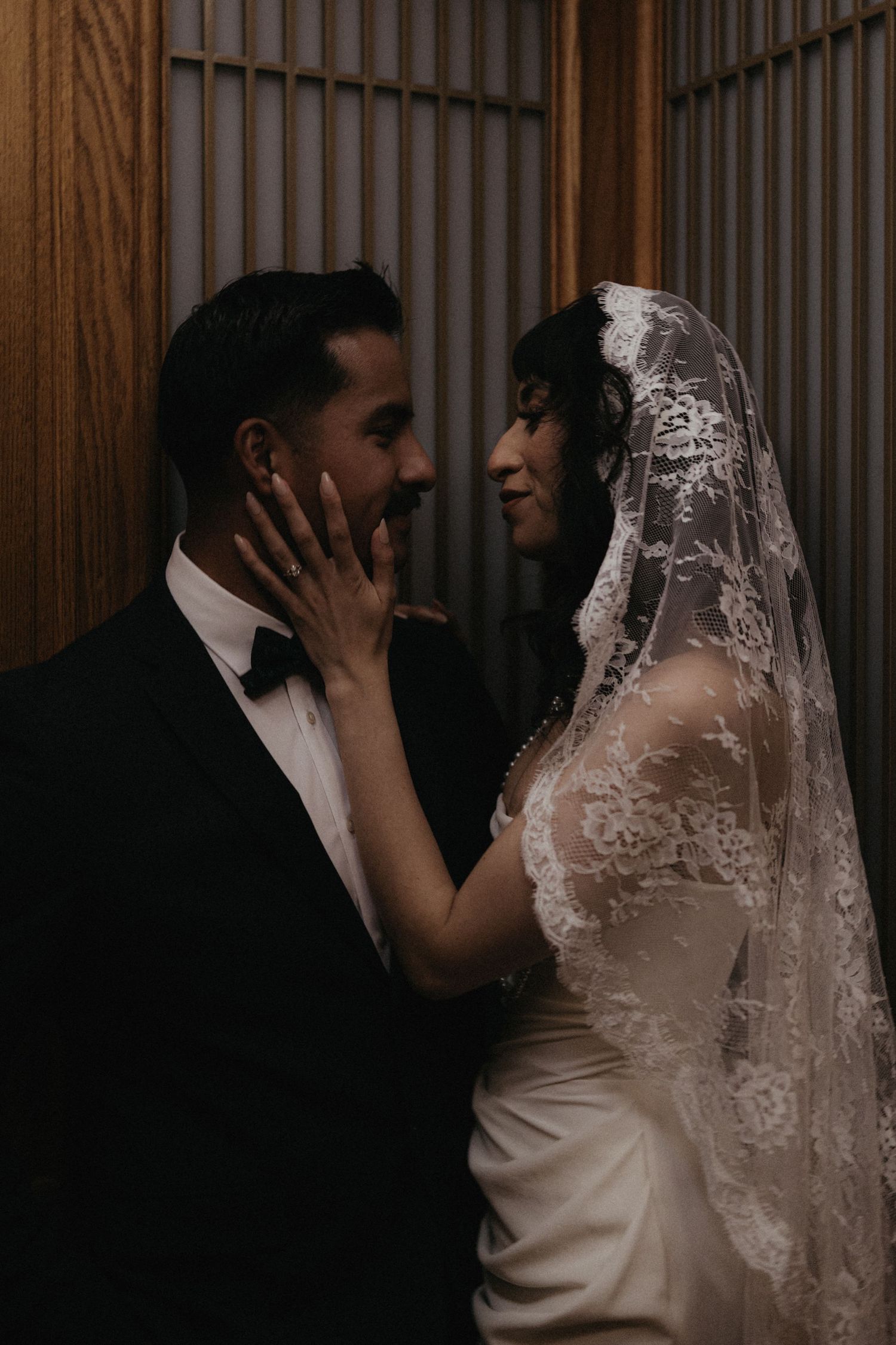 An intimate wedding portrait showing a couple sharing a loving moment in a dimly lit setting.