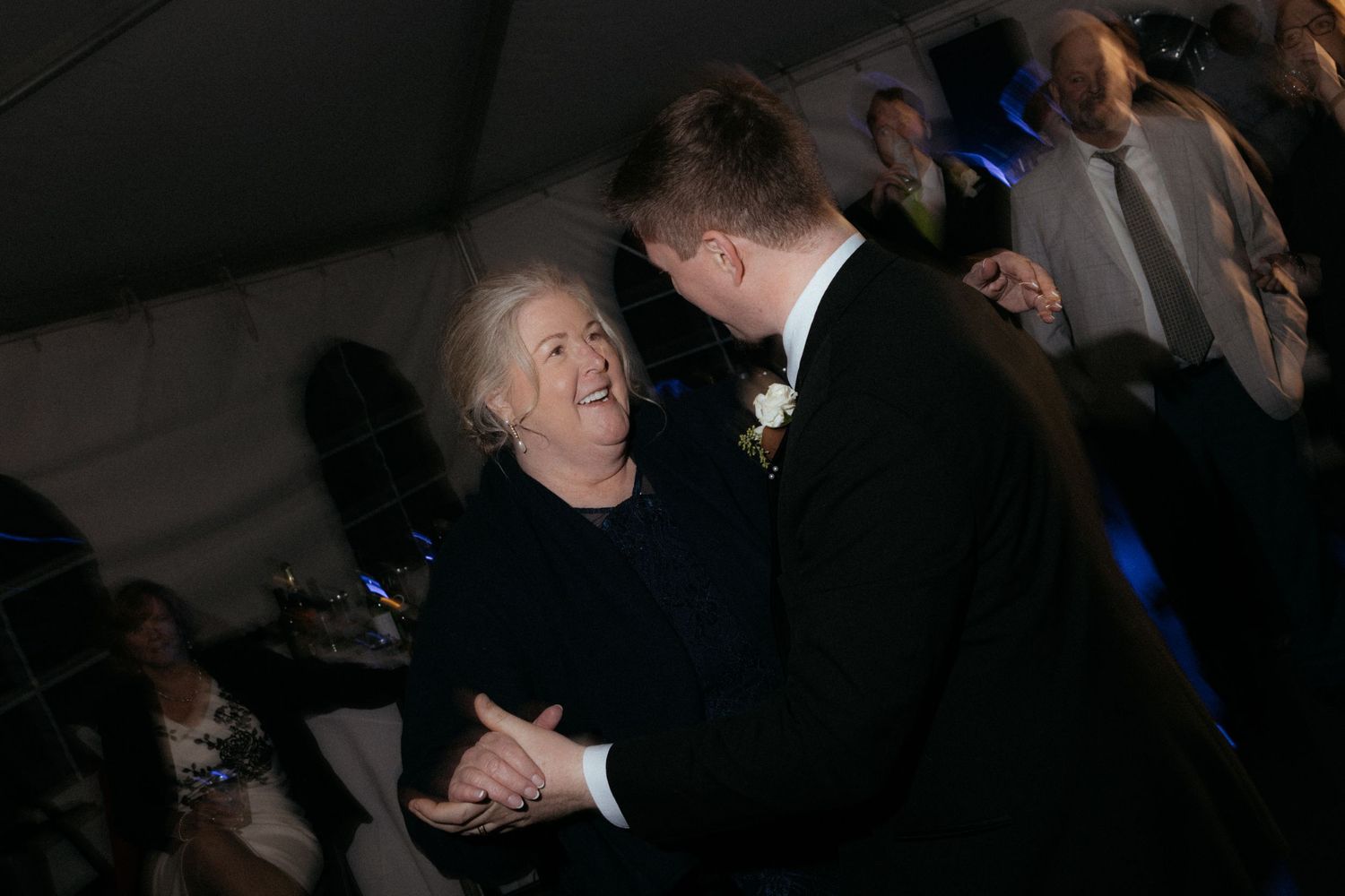 Wedding guests dancing and celebrating on a dark dance floor with atmospheric lighting.