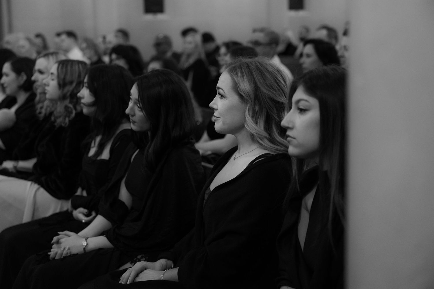 A crowd of people sits attentively in an auditorium during what appears to be a presentation or lecture.