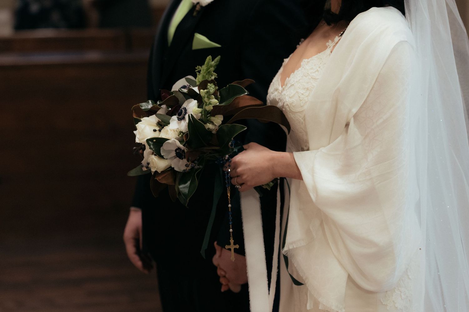 A couple in formal wedding attire holds hands during a traditional church ceremony.