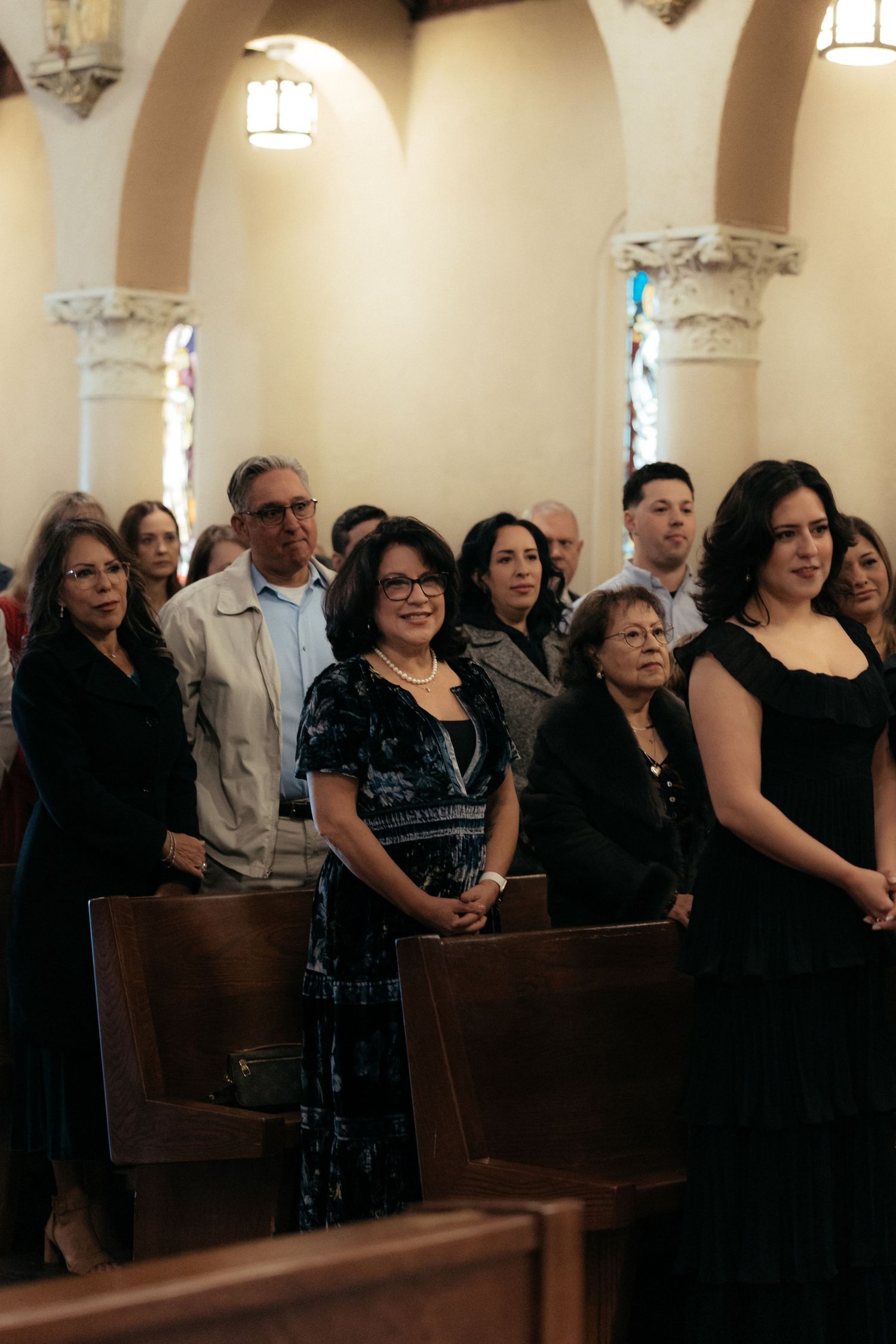 Wedding guests seated in wooden church pews during a ceremony.
