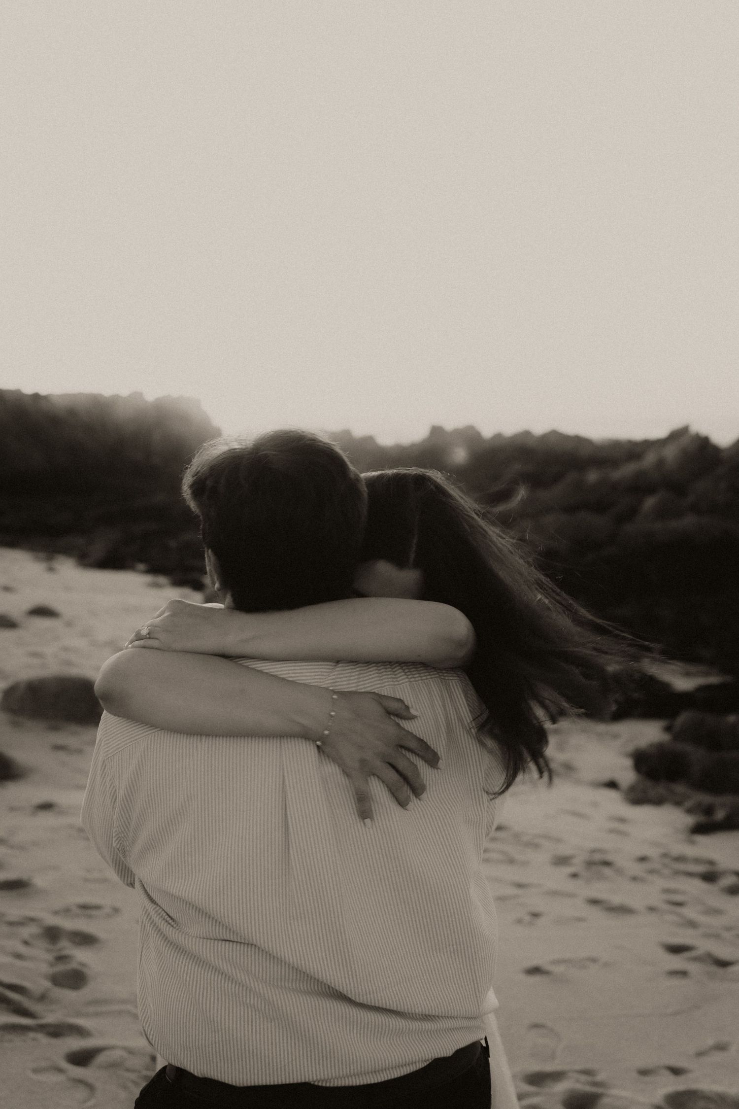 A black and white photo sequence showing two people embracing on a sandy beach in a romantic moment.