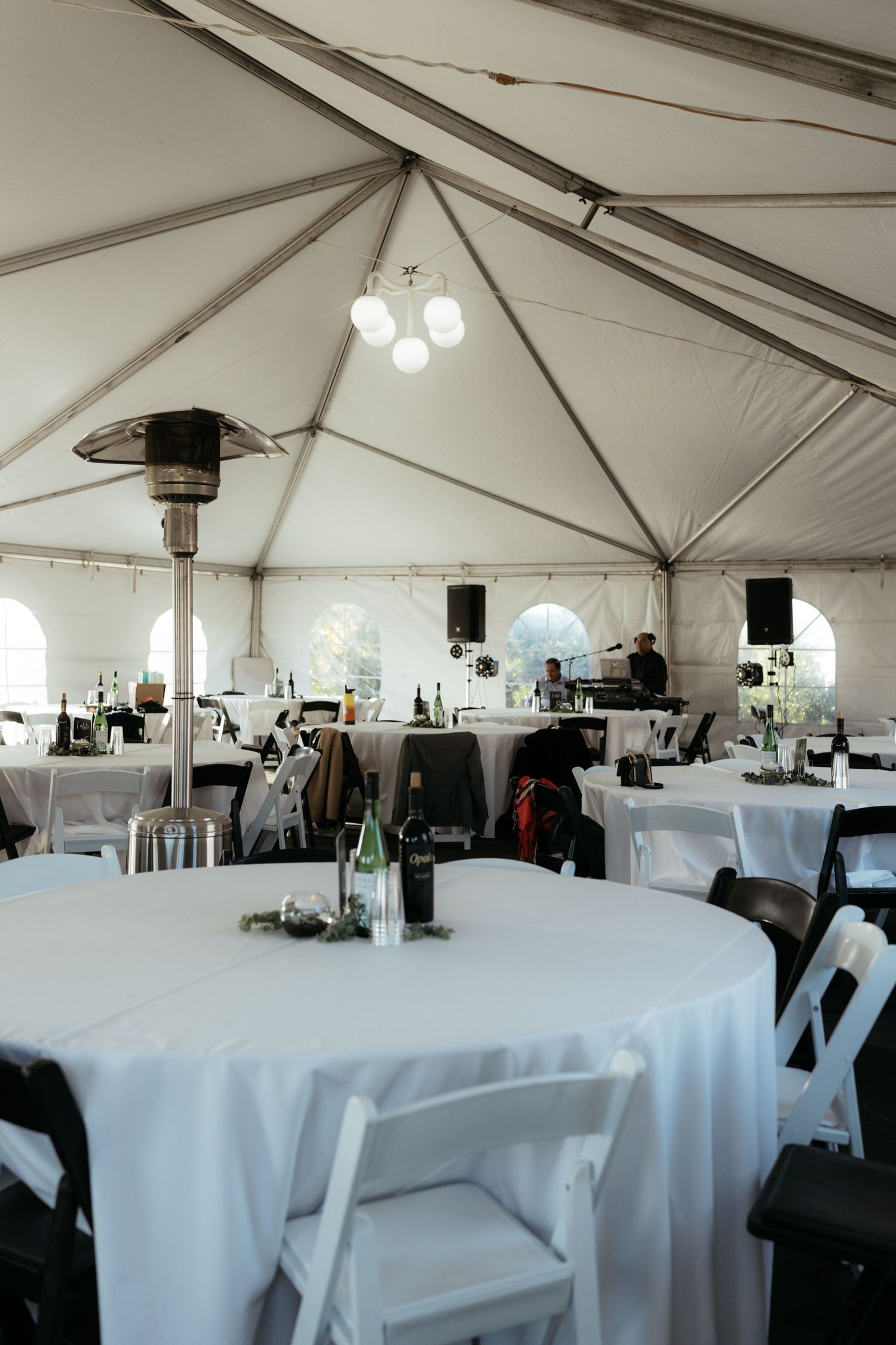 Large white event tent interior with round tables and chairs set up for a reception.