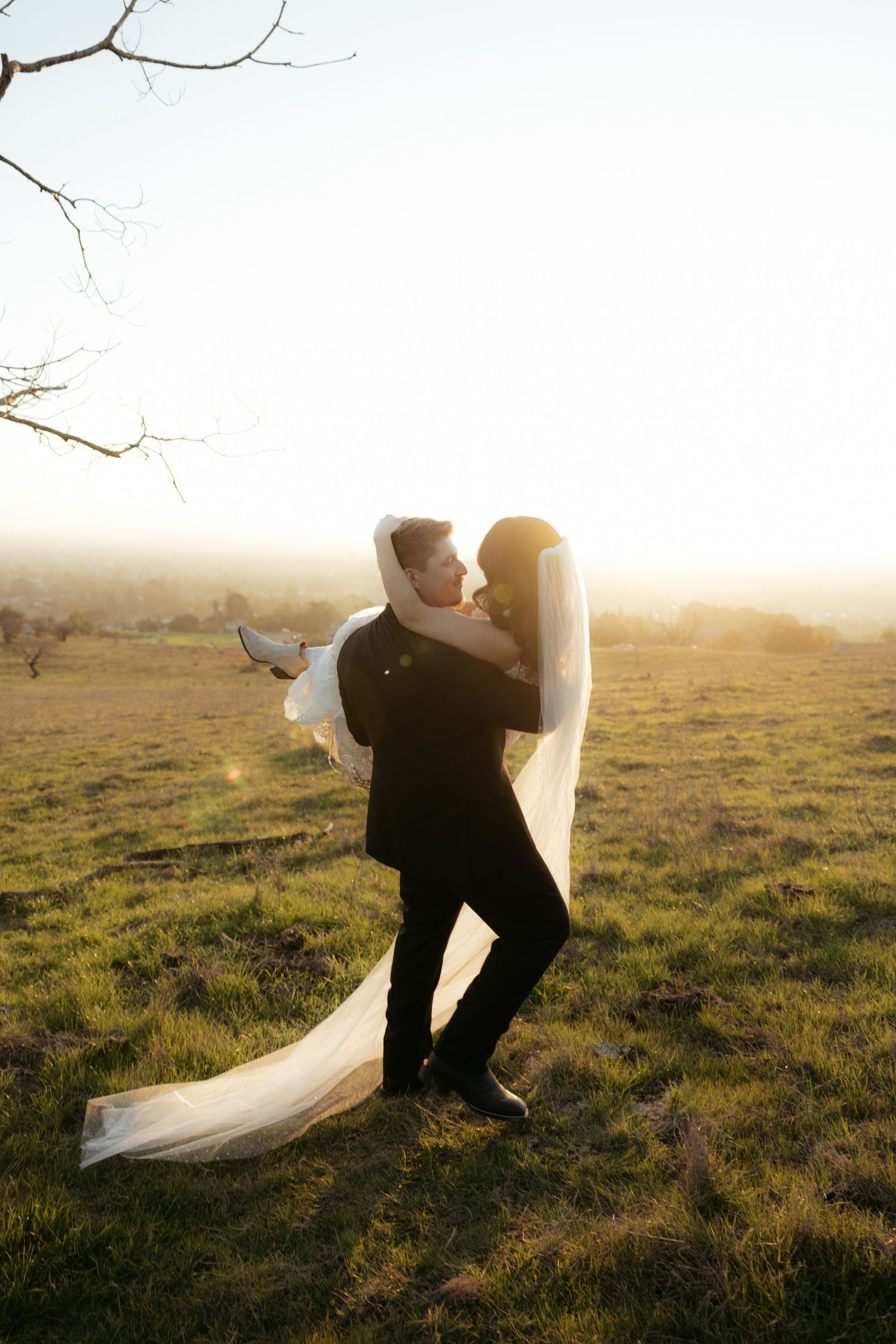 Romantic silhouette of newlyweds embracing in a sunlit meadow during golden hour.