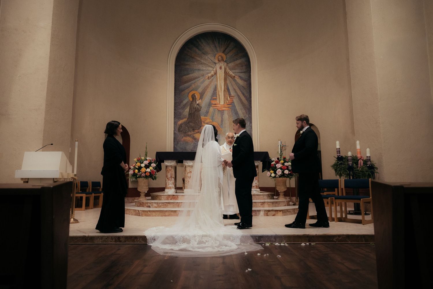 A wedding ceremony takes place in a church with stained glass windows and traditional decor.