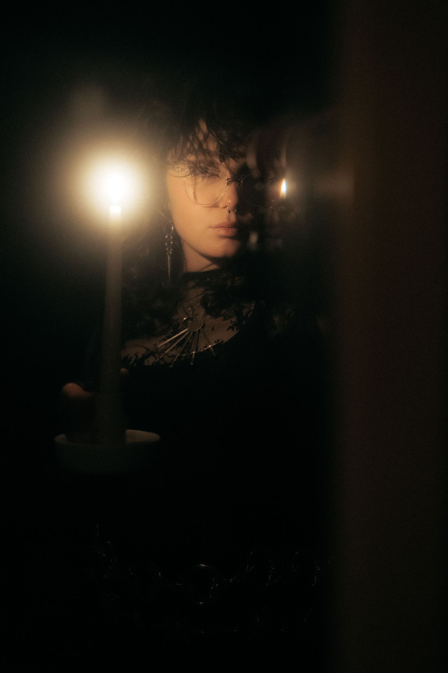 Moody dark portrait with dramatic rim lighting creating a mysterious silhouette against black background.