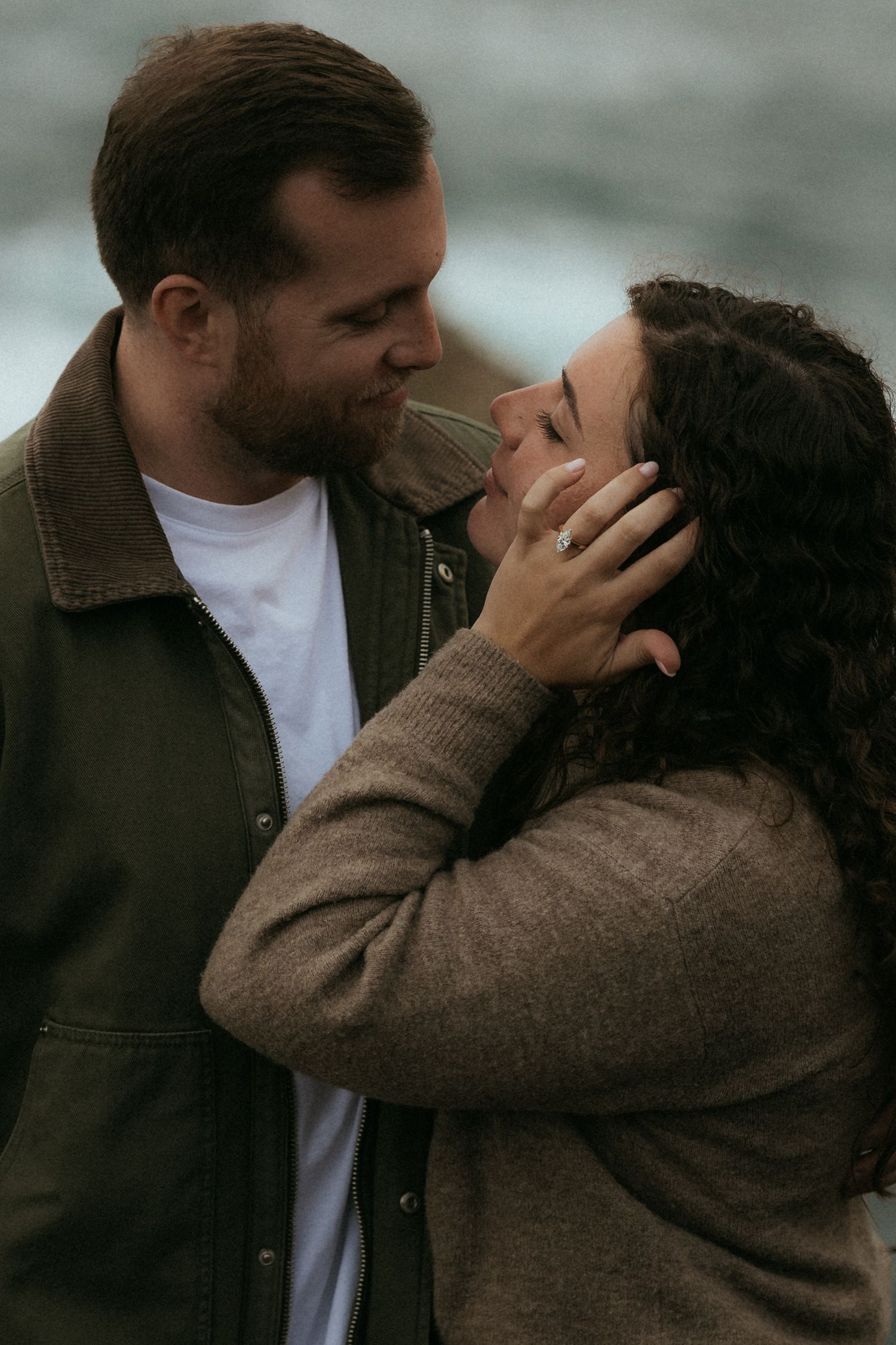A romantic couple shares an intimate moment in moody lighting while wearing casual clothing.