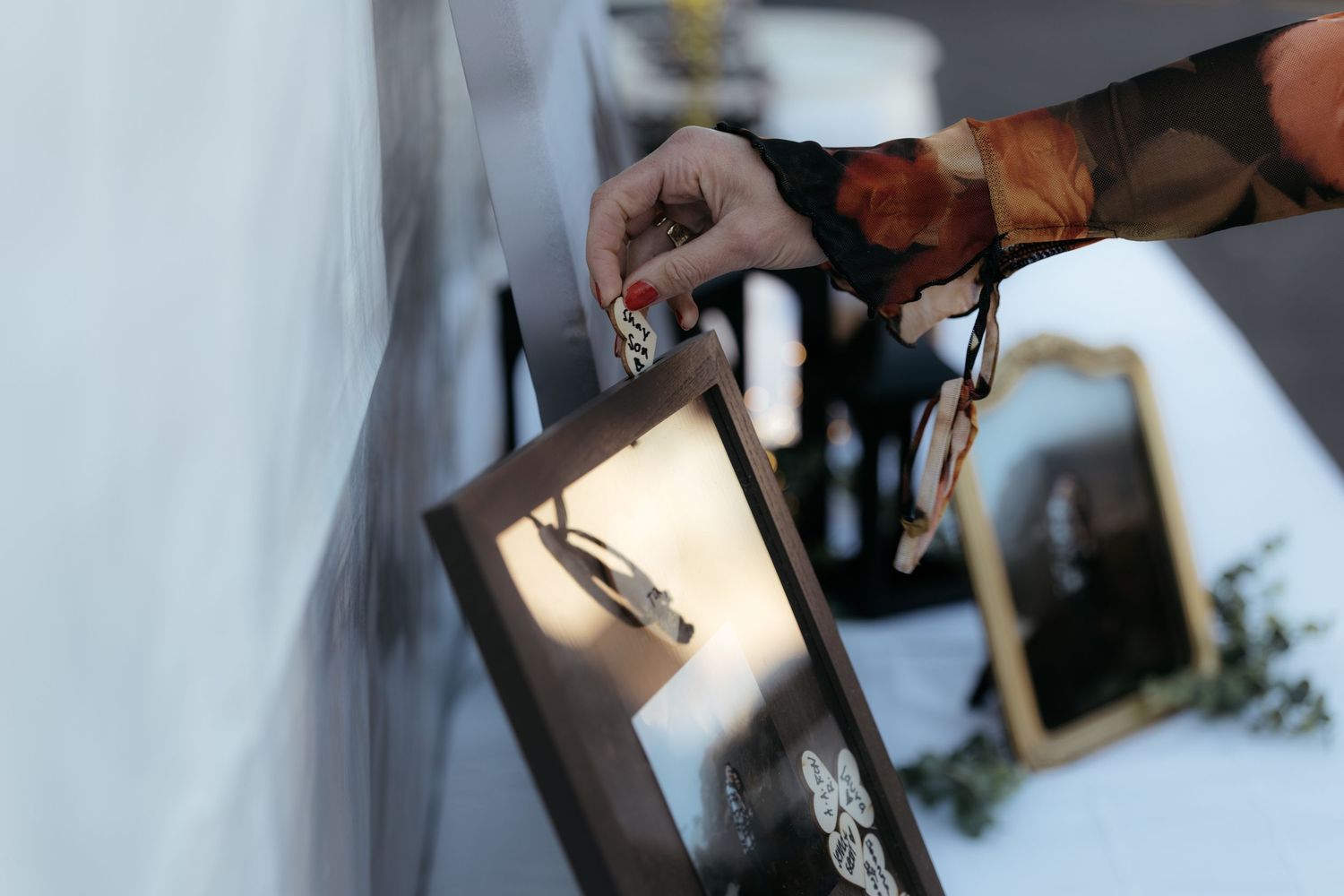 Wedding guests writing messages in a guestbook at an outdoor venue.