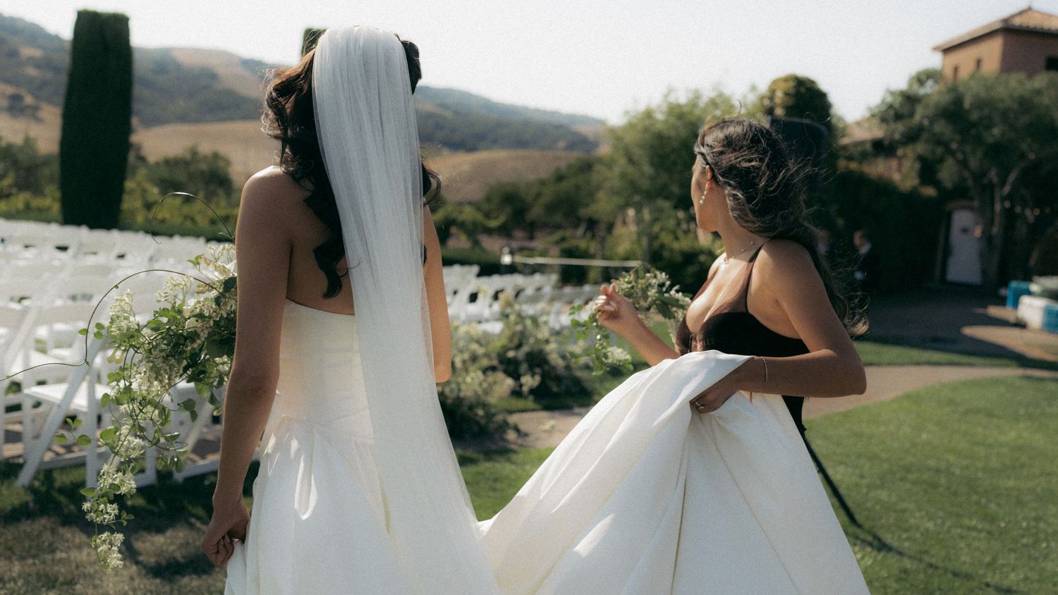 A wedding ceremony in a scenic outdoor setting with mountains and greenery in the background.