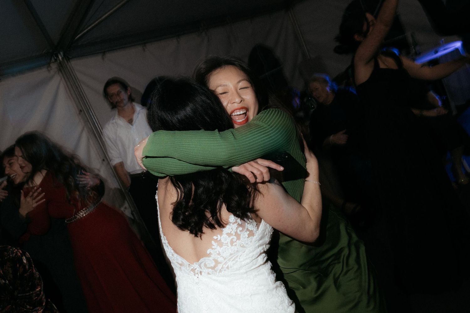 Guests dancing and celebrating at a dimly lit wedding reception.