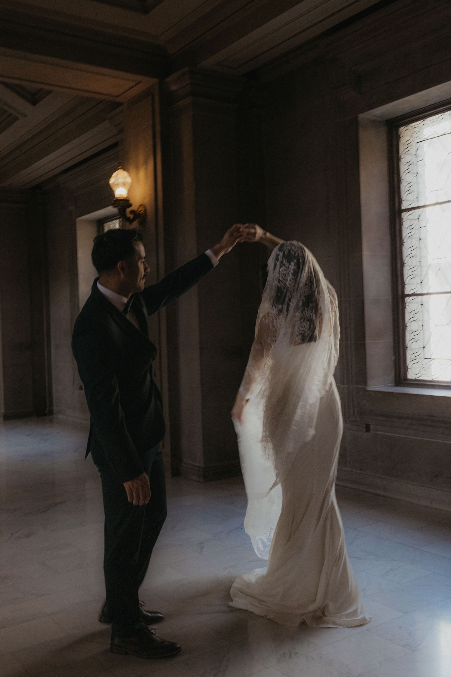 A romantic black and white sequence showing a couple in wedding attire dancing in an elegant hallway.