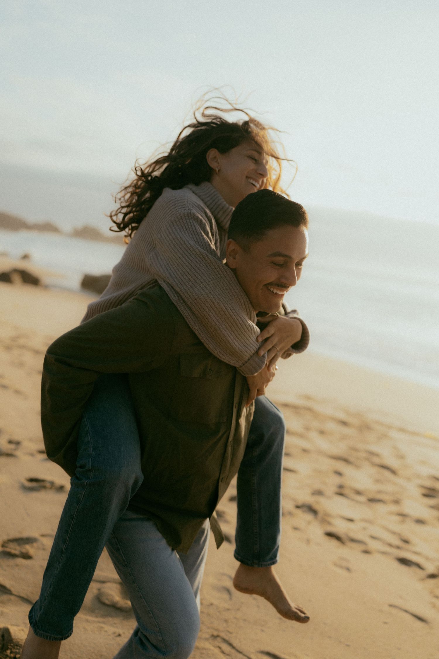 Couple sharing intimate moments on sandy beach at sunset.