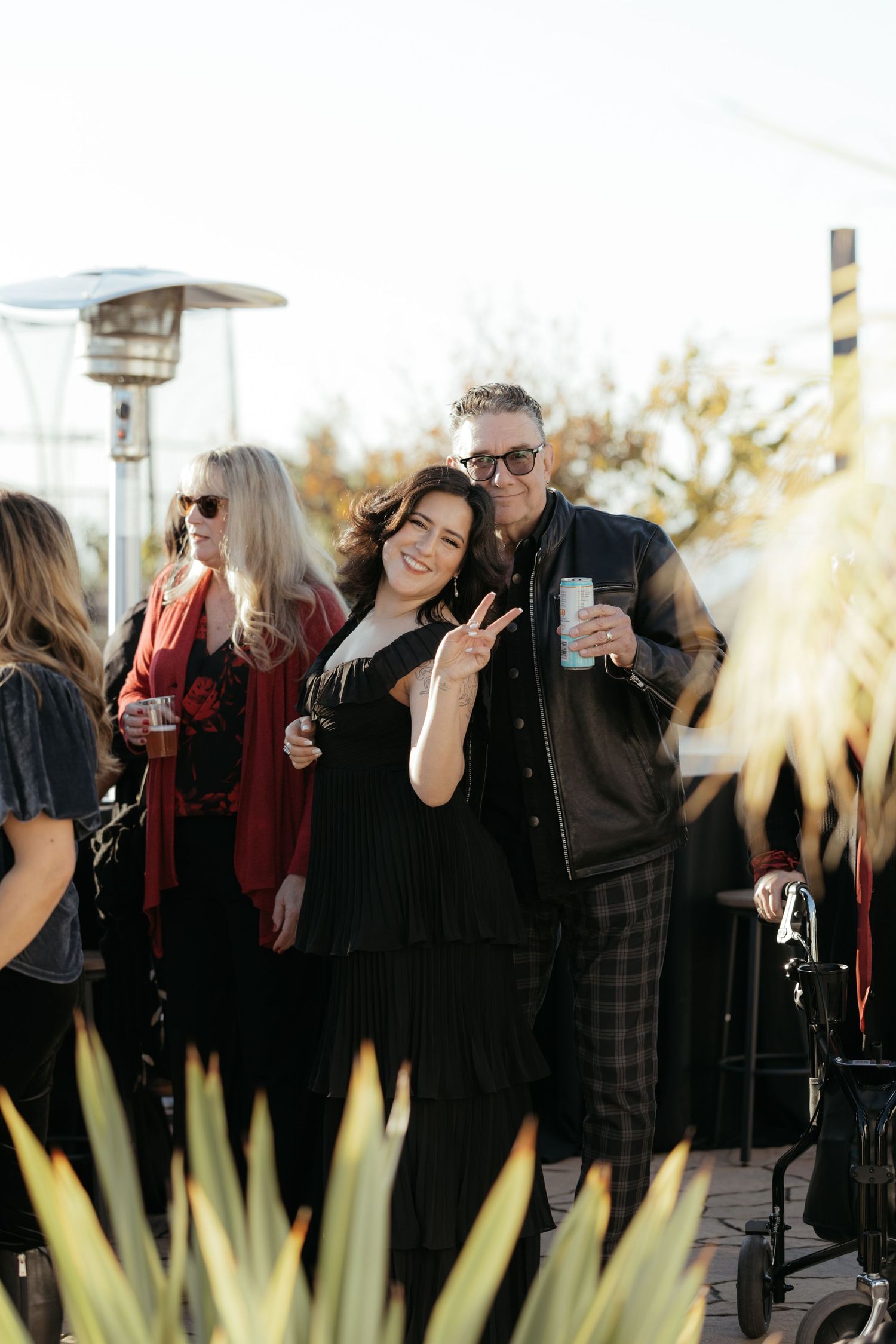 Outdoor gathering of guests in dark attire with sunlit agave plants in foreground.