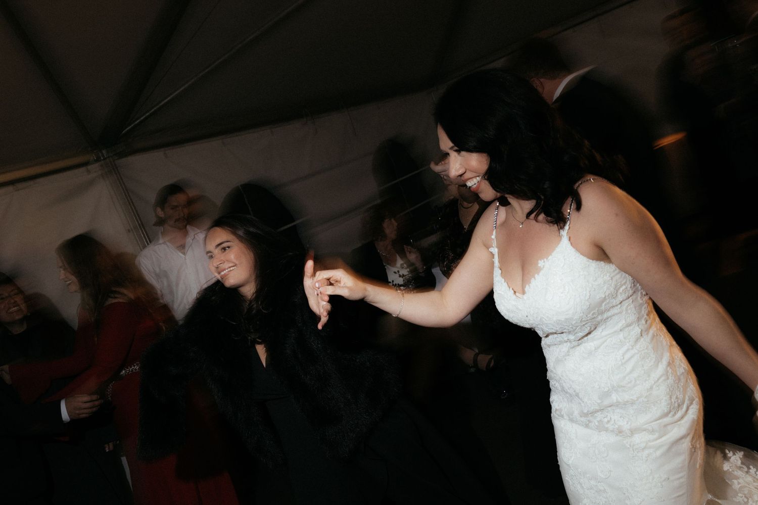 Wedding guests dancing and celebrating on a dimly lit dance floor.