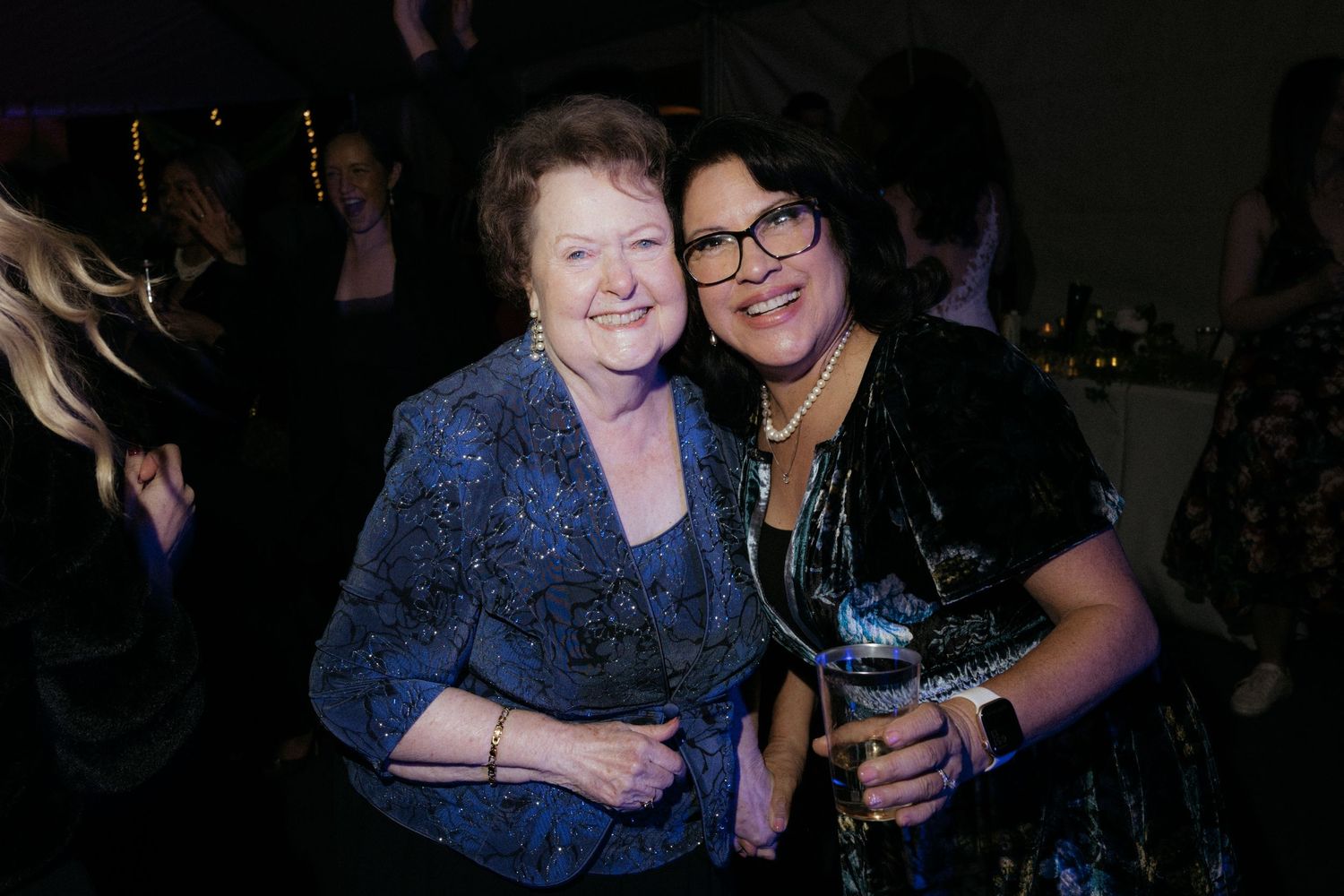 Friends sharing hugs and laughter at a nighttime celebration.