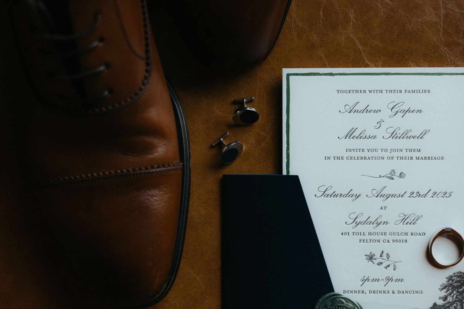 Close-up view of elegant wedding invitations and stationery laid out on a dark wooden surface.