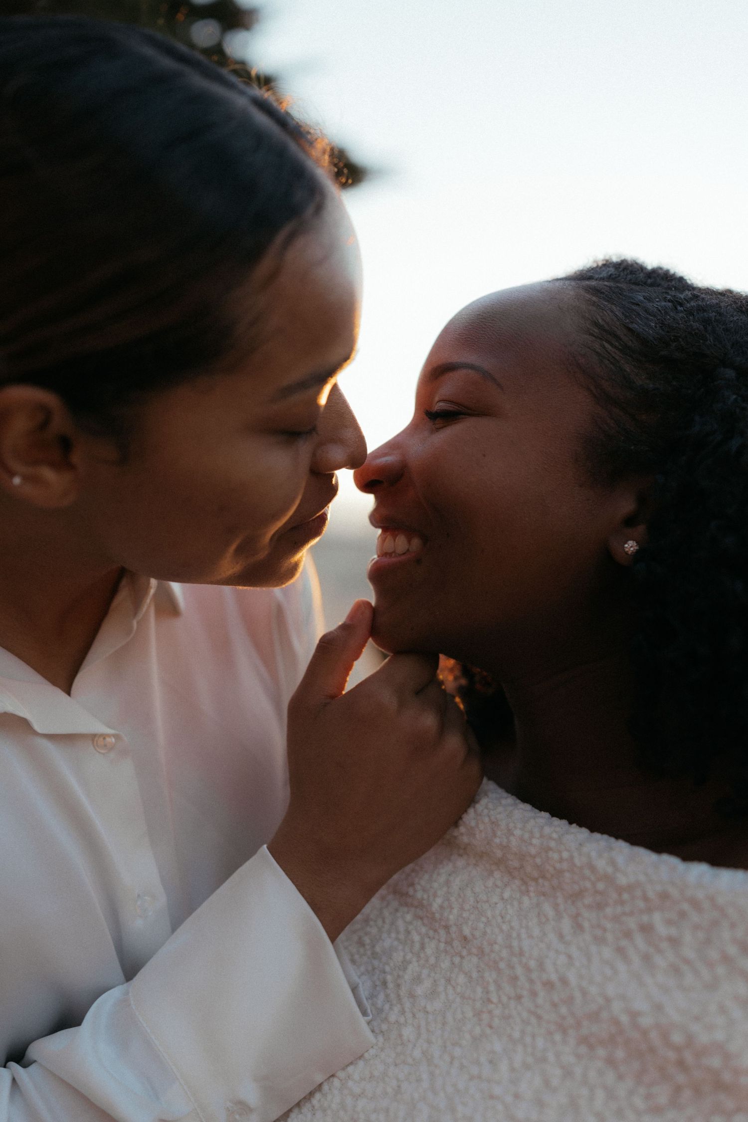 A tender moment between two people in white clothing sharing an intimate embrace in soft lighting.