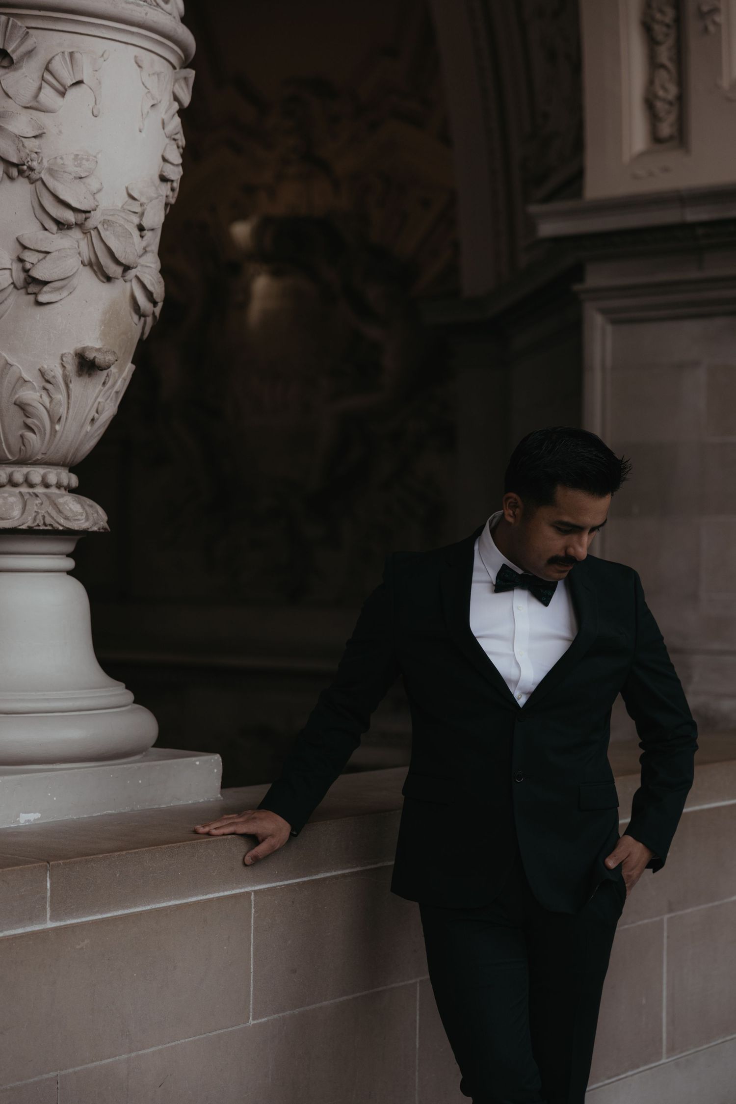 Dark silhouettes against ornate stone columns create a dramatic architectural wedding portrait series.