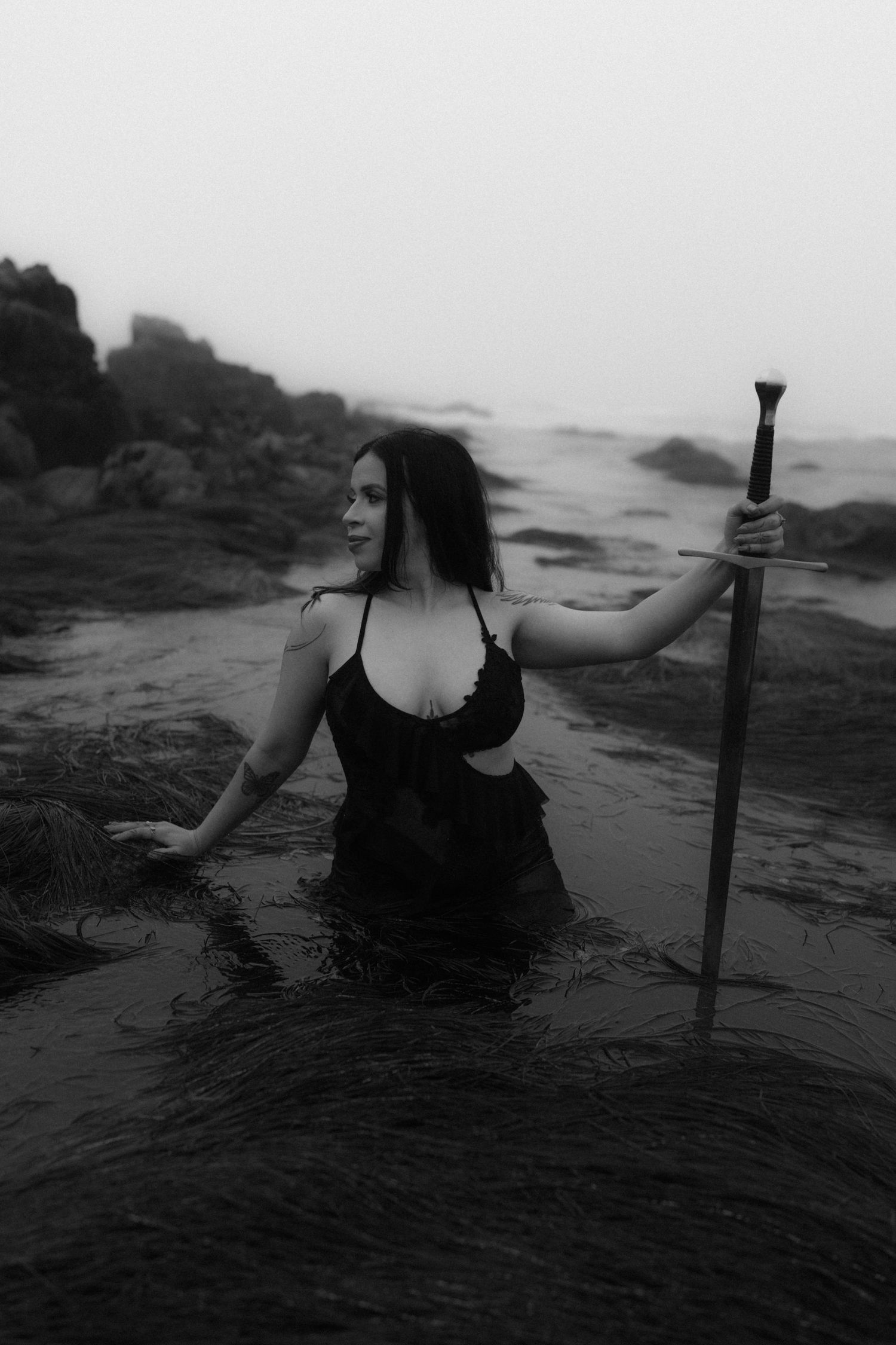 Silhouette emerges from dark waters against misty coastal backdrop.