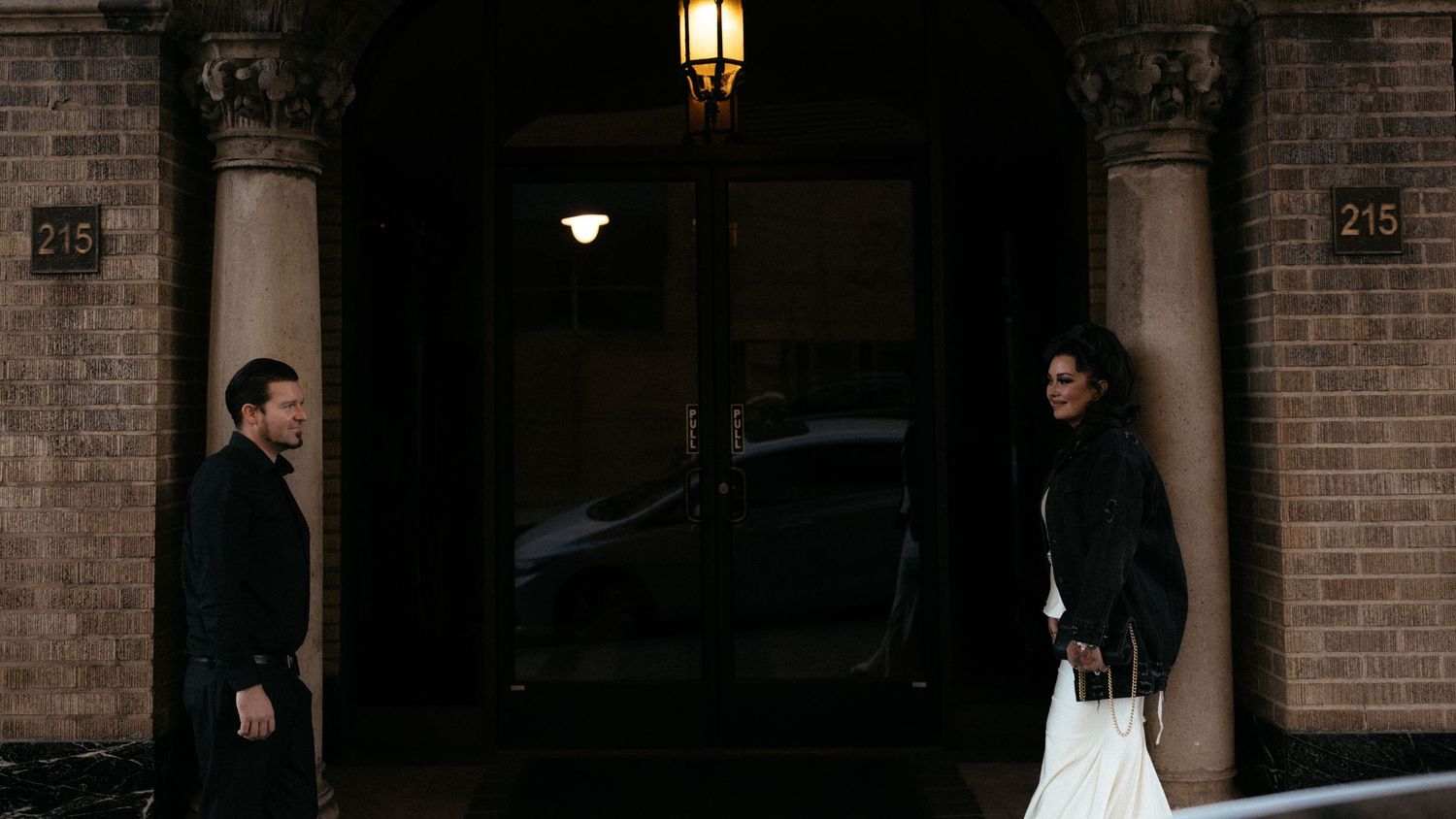 Brick storefront entrance with lantern lighting and floral decorations at dusk.