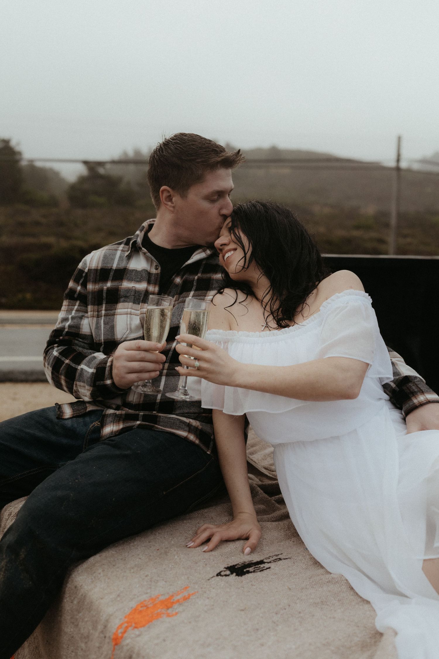 Couple in casual attire sharing tender moment in back of truck.
