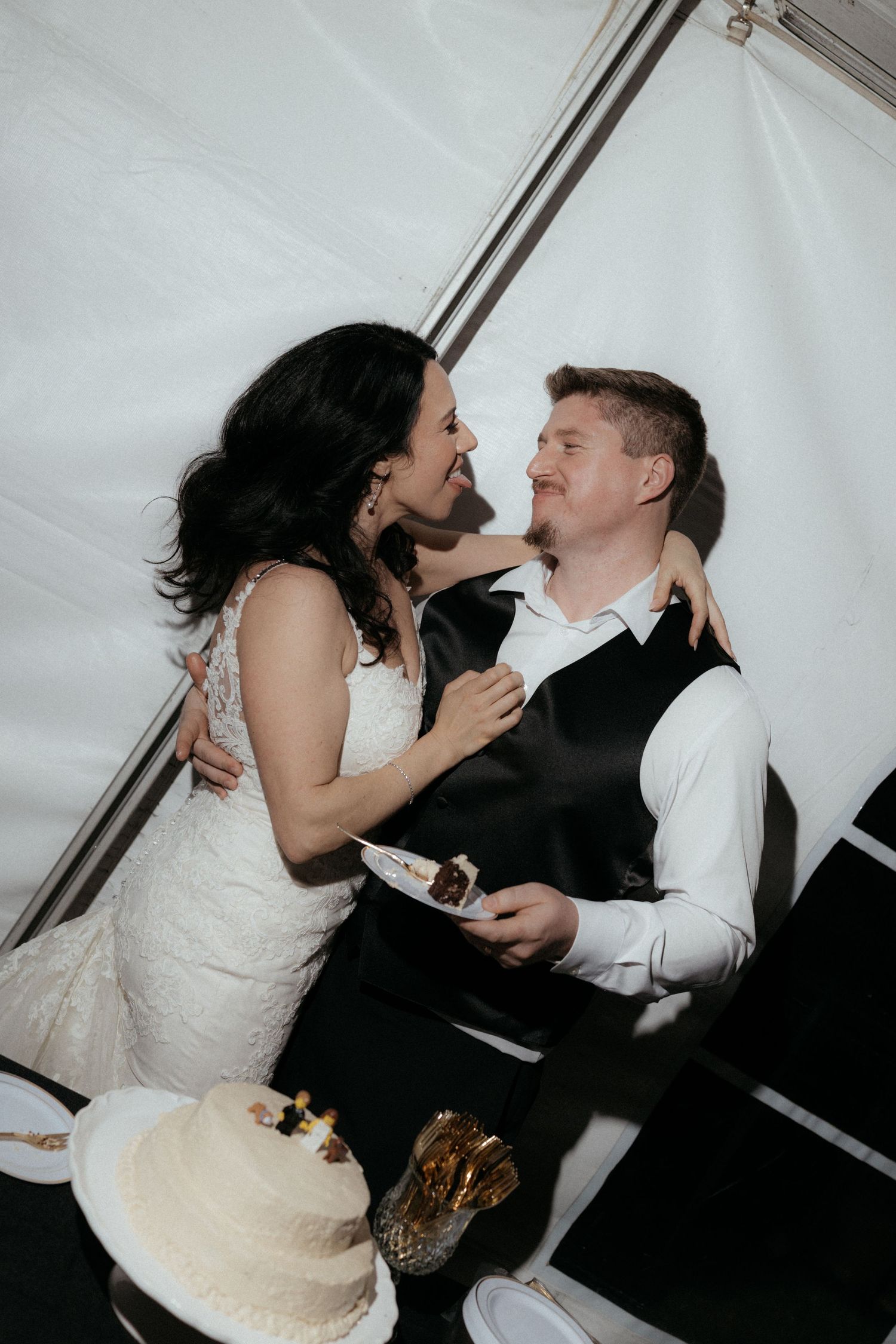 A bride and groom playfully share wedding cake during their reception celebration.