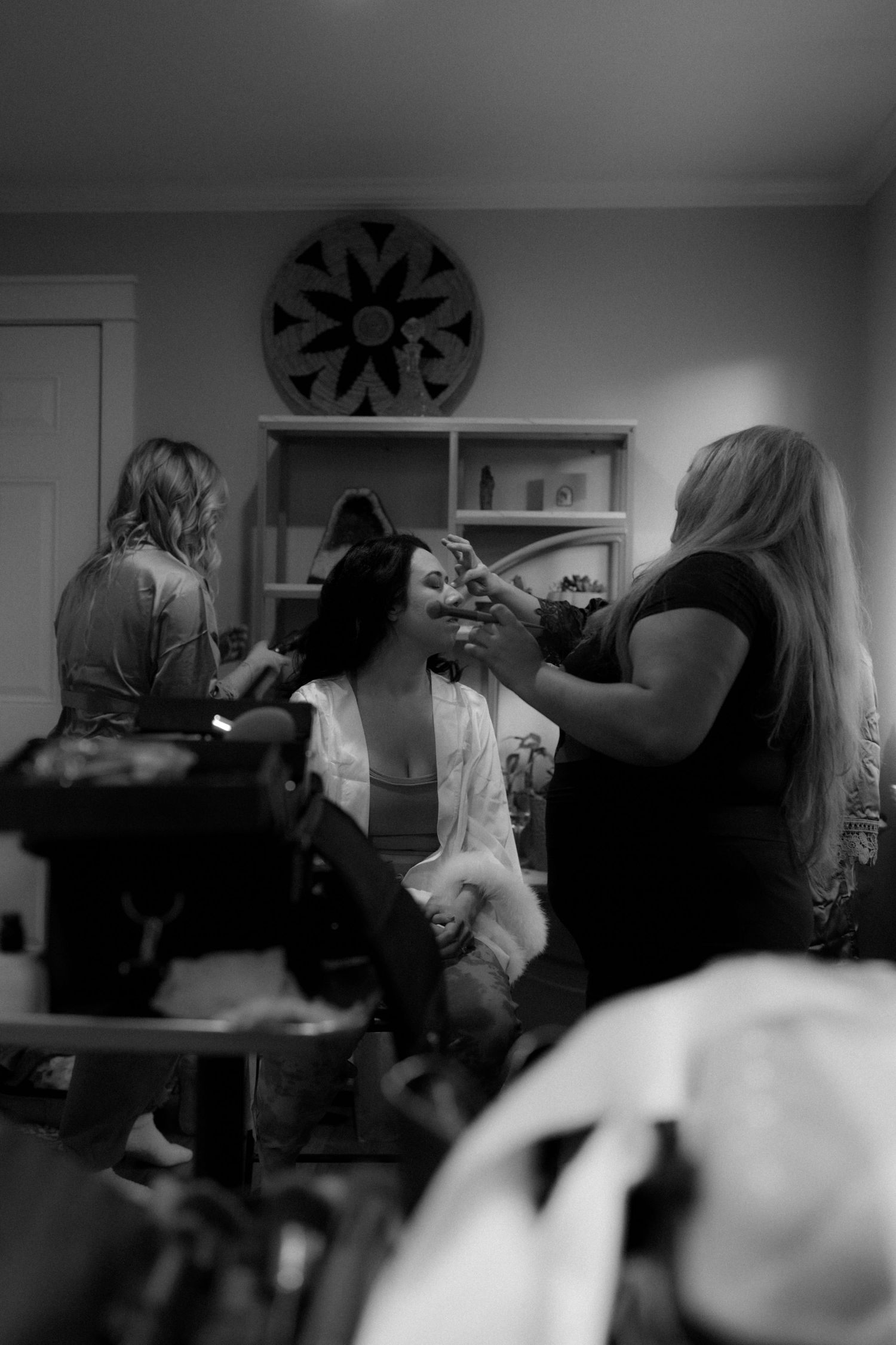 Black and white image showing people getting ready in a room with a decorative ceiling fan.