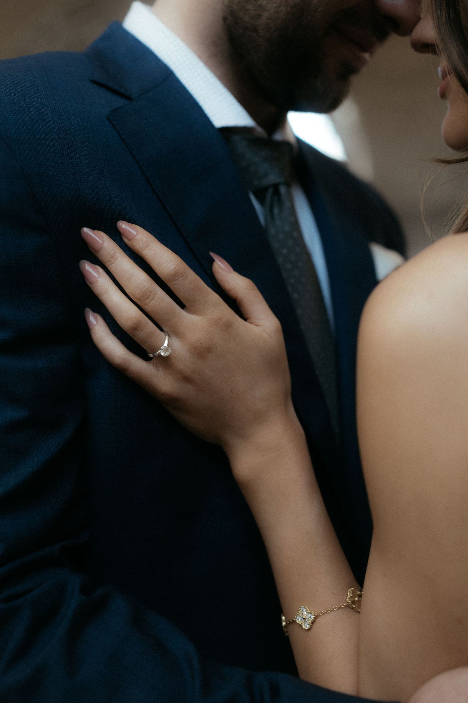Close-up view of hands embracing during a romantic wedding moment with elegant attire and jewelry.