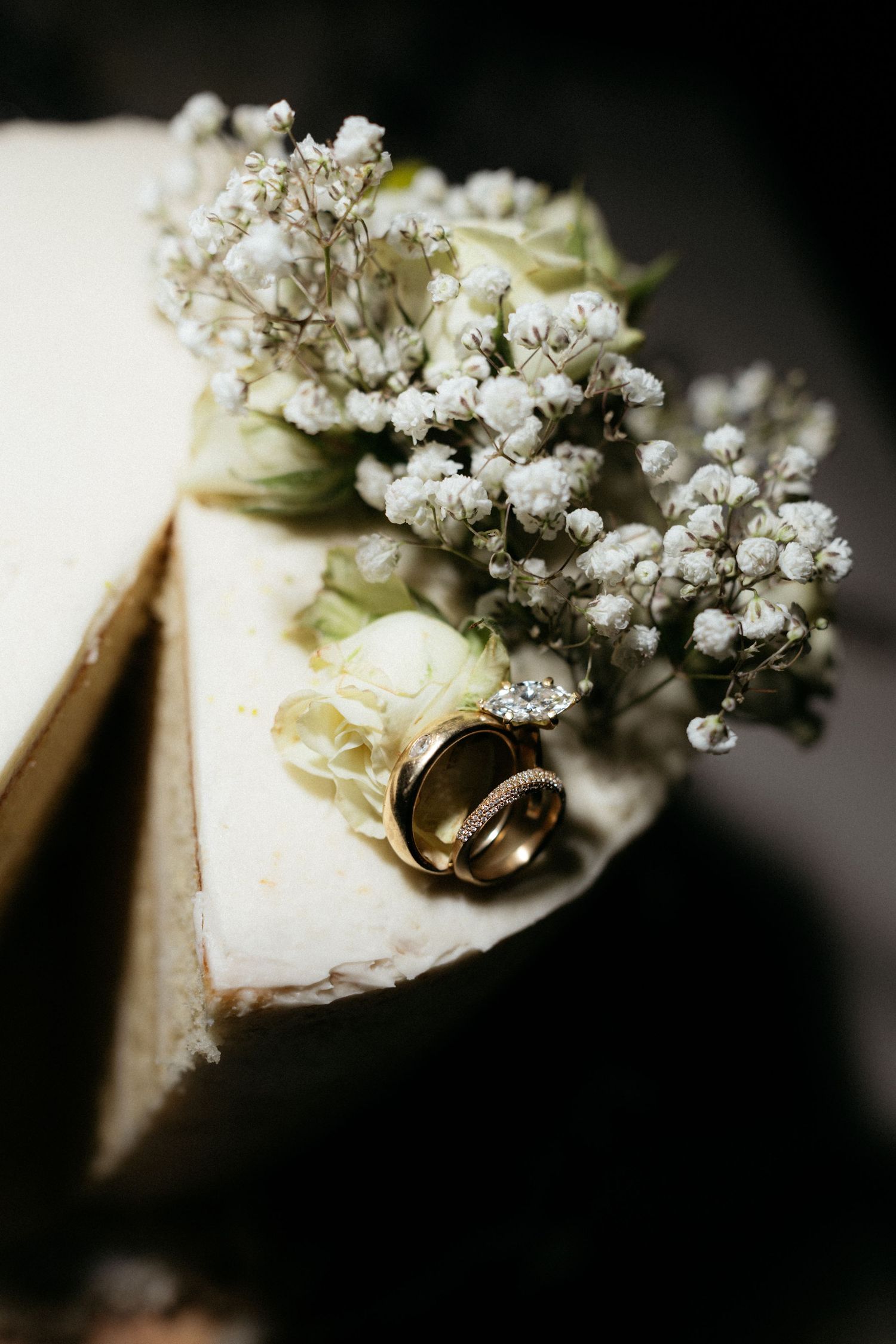 Wedding rings and diamond engagement ring resting on an old book with delicate white baby's breath flowers.