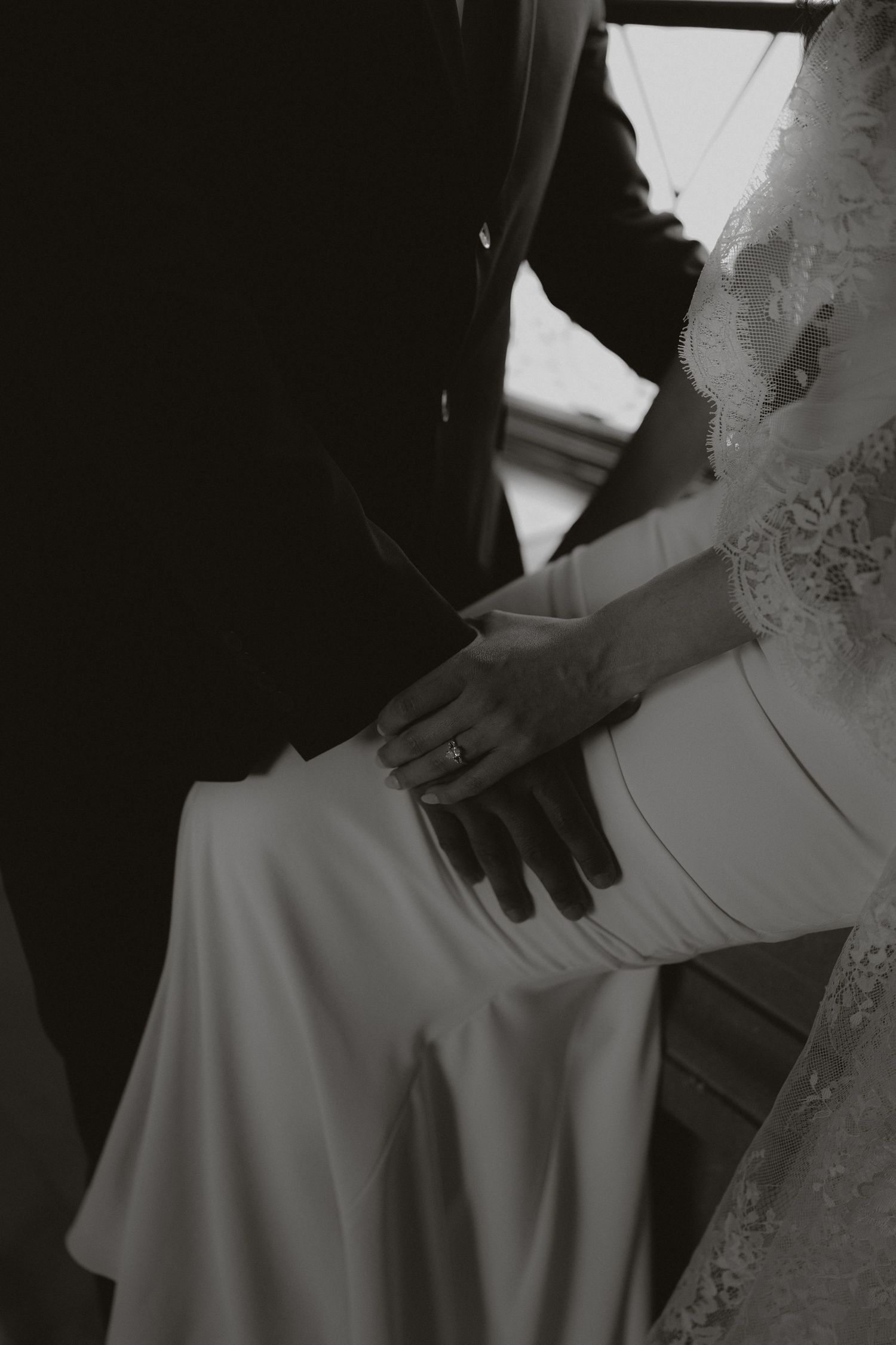 Close-up details of a wedding dress and couple's intimate poses in black and white.