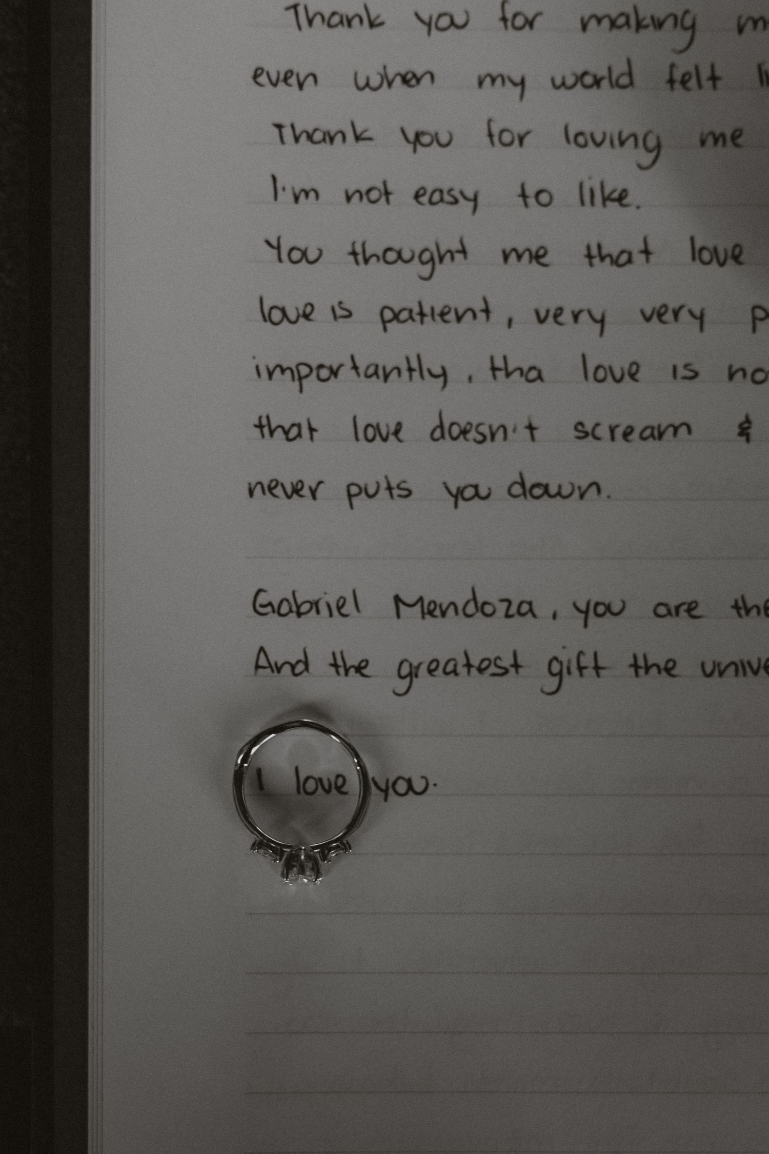 A handwritten love note with a wedding ring placed on the paper.