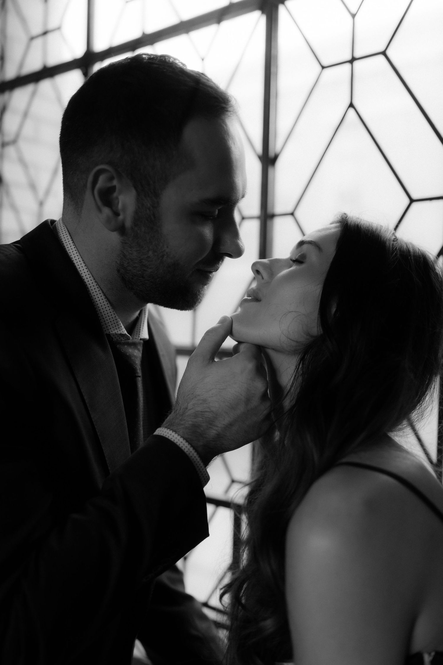 A romantic black and white photo series shows a couple sharing intimate kisses against a geometric patterned background.
